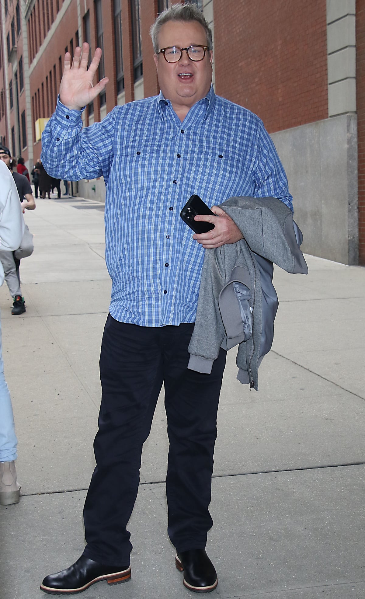 Eric Stonestreet keeps it laid-back and stylish in a blue plaid shirt and dark jeans, grounding the outfit with rugged black leather boots featuring a contrasting brown sole