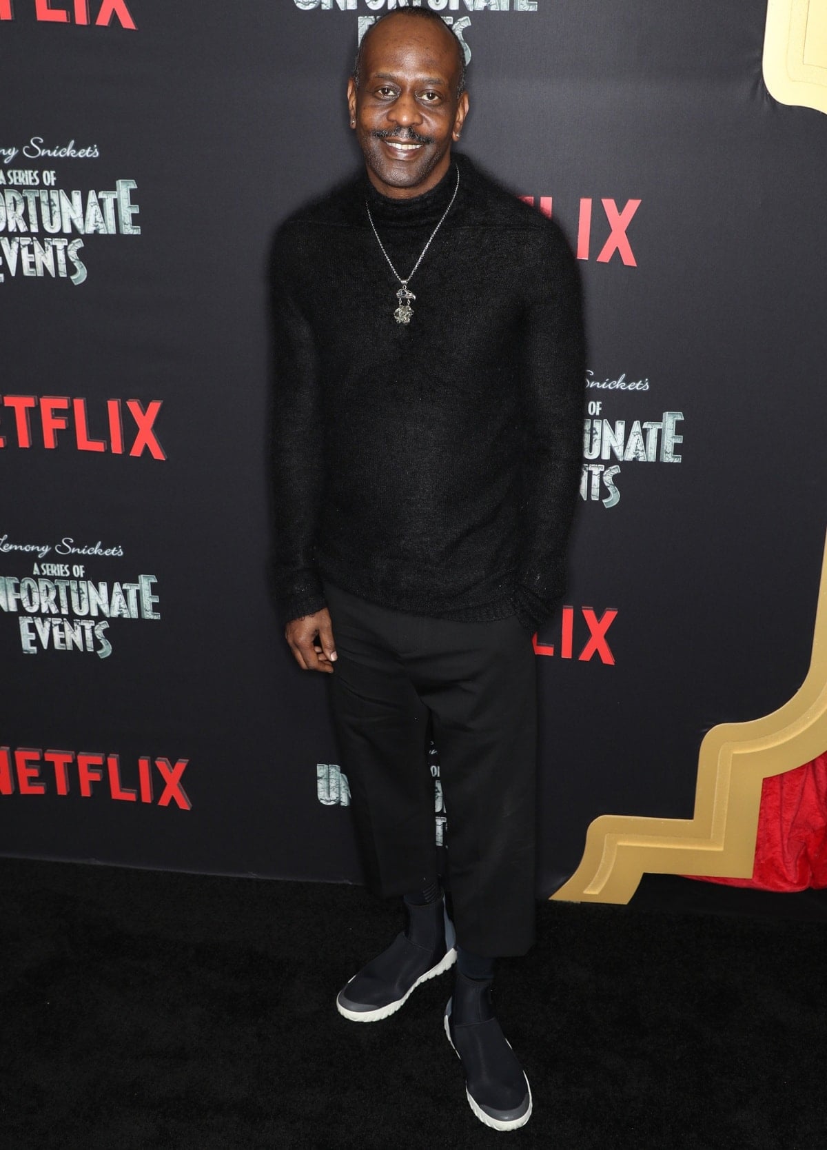 Malcolm Barrett exudes casual cool at the A Series of Unfortunate Events premiere, pairing a black knit sweater with cropped trousers and sleek slip-on sneakers for a sharp, modern look