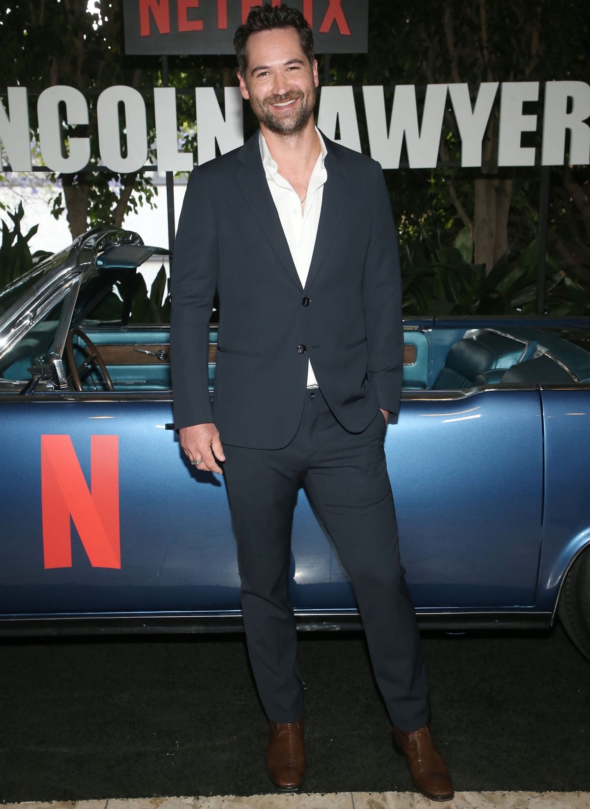 Manuel Garcia-Rulfo, standing tall at 6 feet 2 ¼ inches (188.6 cm), looked sharp in a navy suit paired with sleek brown leather dress shoes at The Lincoln Lawyer Netflix event, effortlessly blending modern polish with classic style