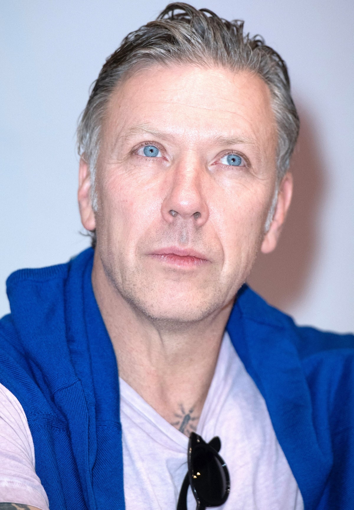 Mikael Persbrandt attends a press event looking effortlessly cool in a casual pale tee layered with a royal blue sweater and dark sunglasses, showcasing his signature Nordic charm and confident presence