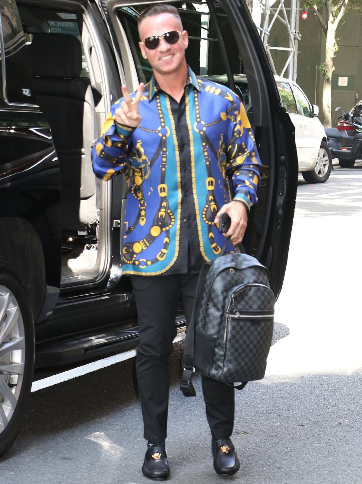 Mike “The Situation” Sorrentino stepped out in sleek black dress shoes with gold Medusa medallions, pairing them with fitted black pants and a bold Versace-inspired blue and gold printed shirt
