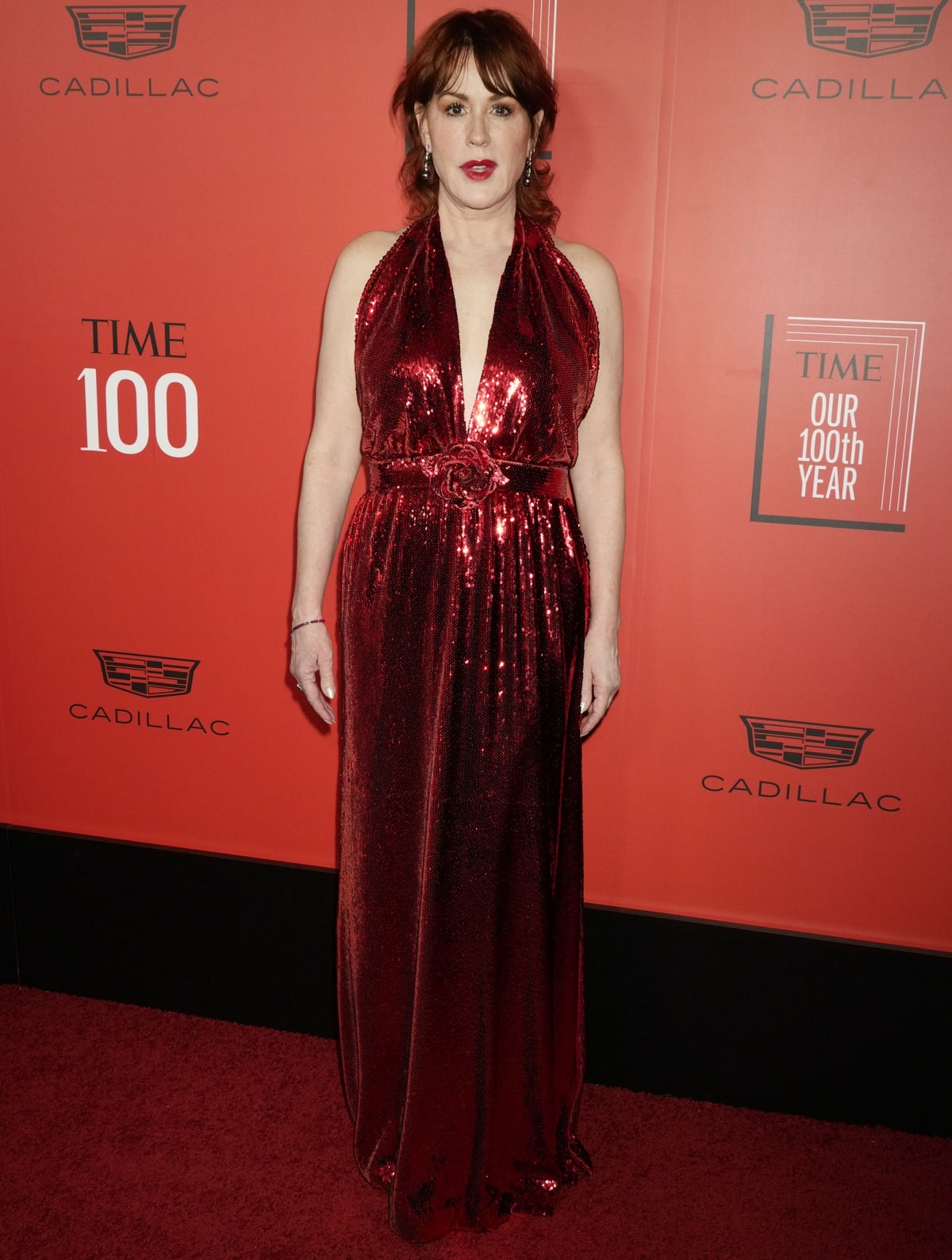 Molly Ringwald glitters in a floor-length red sequin gown, finished with matching elegant heels on the red carpet