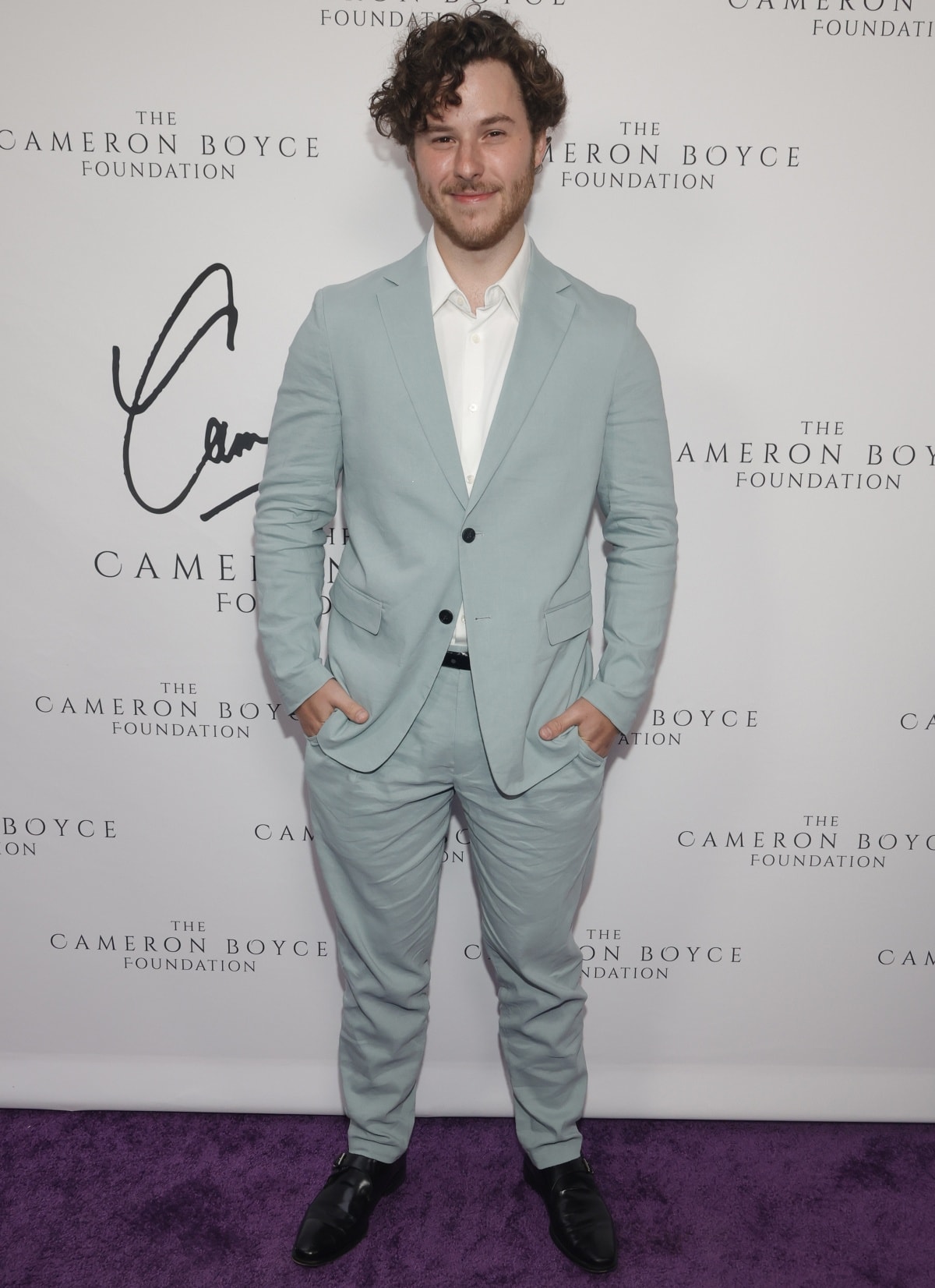 Nolan Gould looks fresh and polished in a pale blue suit and white shirt, finishing the ensemble with sleek black monk strap shoes for a modern twist on classic formalwear