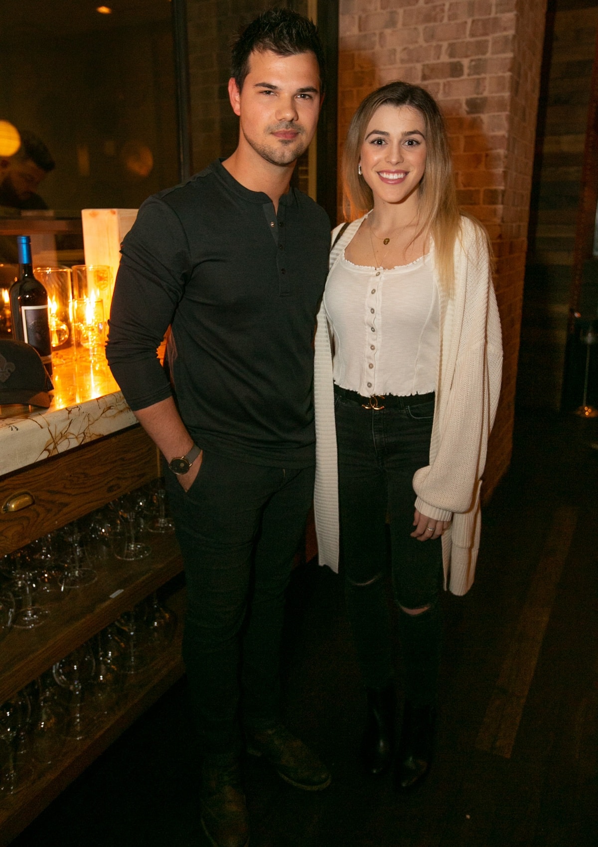 Taylor Lautner and Tay Dome kept it casual and cozy, with Lautner in a black Henley and jeans, while Dome paired a white button-front top with ripped black jeans, ankle boots, and a slouchy cream cardigan