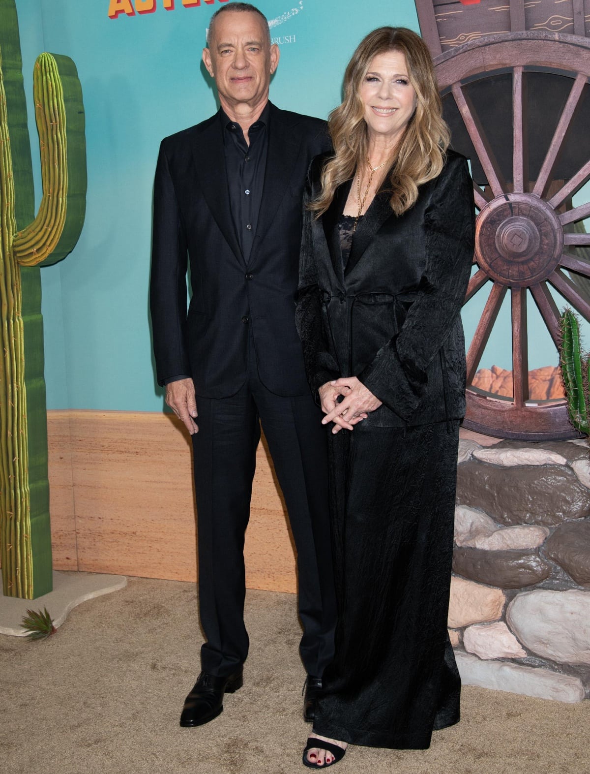 Standing at 5 feet 11 ½ inches (181.6 cm), Tom Hanks complemented his sleek black suit with polished dress shoes, while 5-foot-7 (170.2 cm) Rita Wilson added height in open-toe black heels peeking out beneath her long satin coat