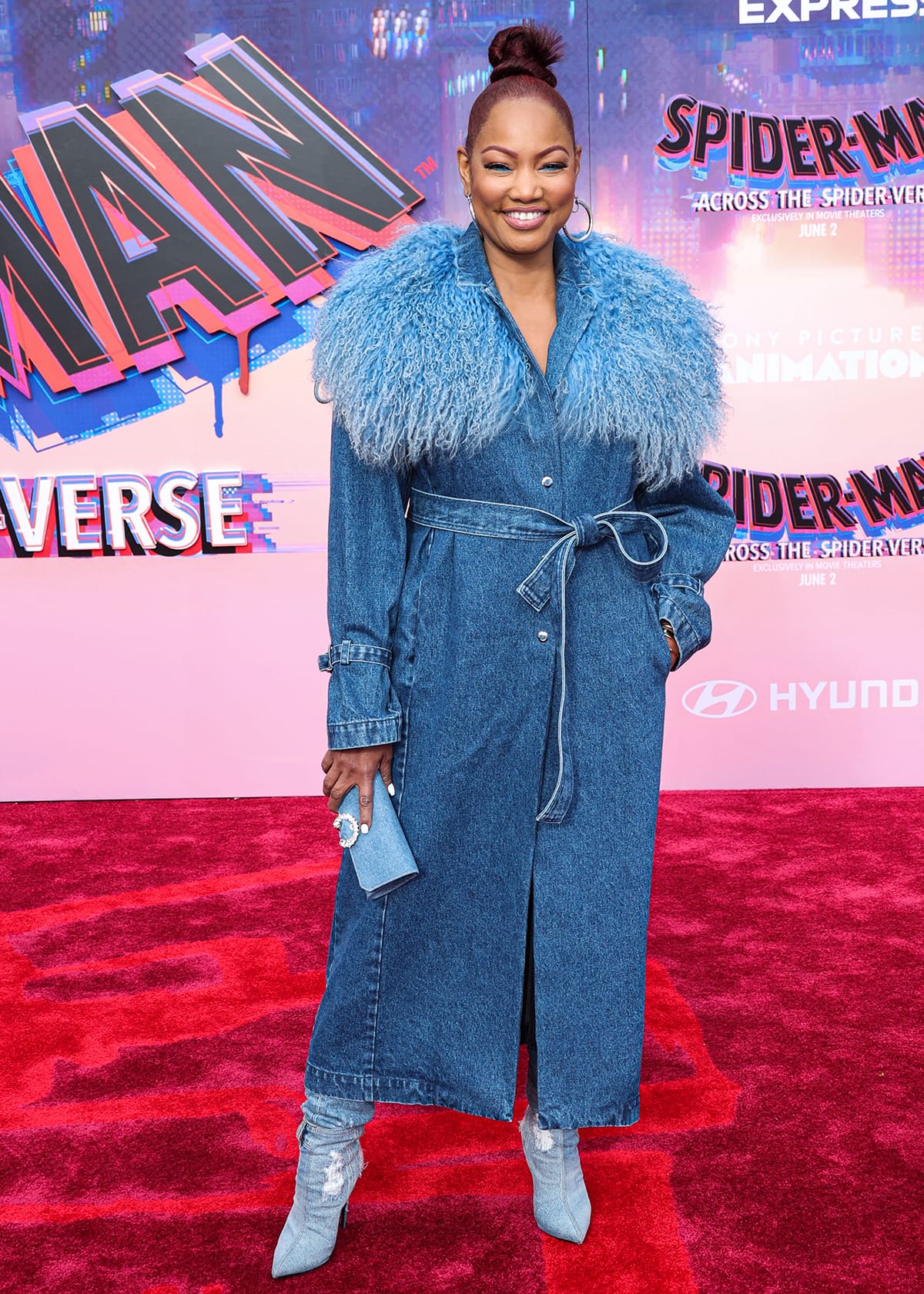 Garcelle Beauvais makes a bold statement at the Spider-Man: Across the Spider-Verse premiere in a belted denim coat with a dramatic textured collar, matching clutch, and distressed denim stiletto boots that showcase her US size 8.5 feet