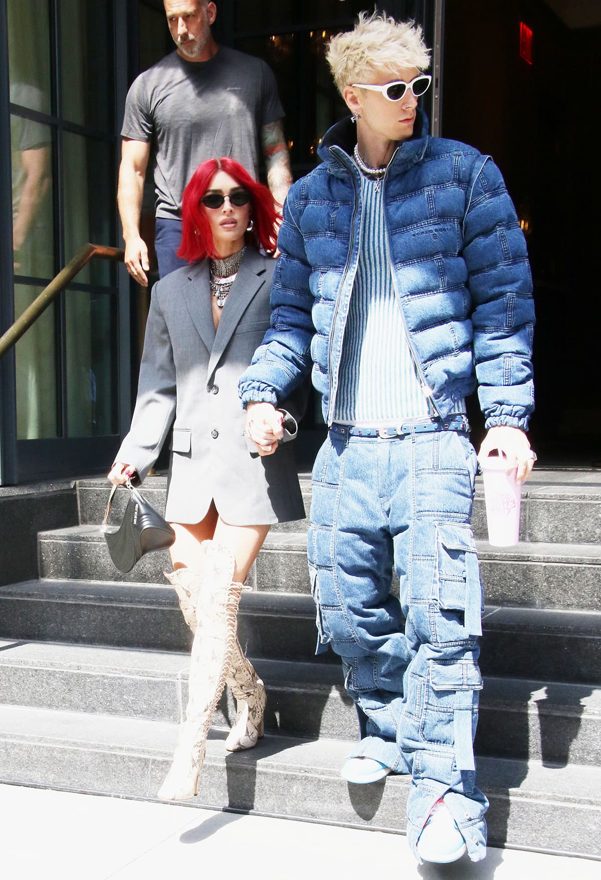 Megan Fox contrasts her bold red bob with an oversized gray blazer dress, grounding the look with lace-up thigh-high snakeskin boots that sharpen the silhouette and elongate her legs
