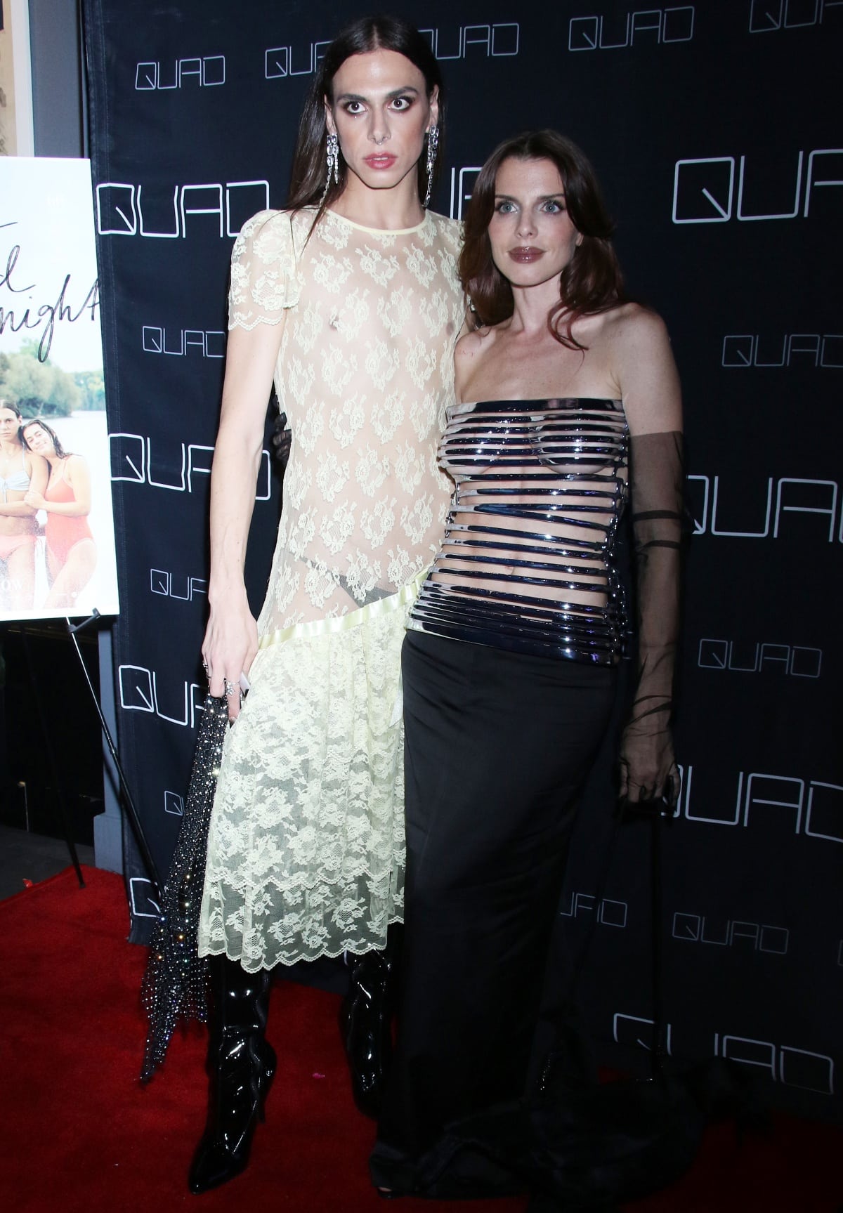 Carmen Madonia towers over Julia Fox on the red carpet at the Something You Said Last Night premiere, wearing a sheer cream lace dress paired with glossy black patent boots and statement drop earrings