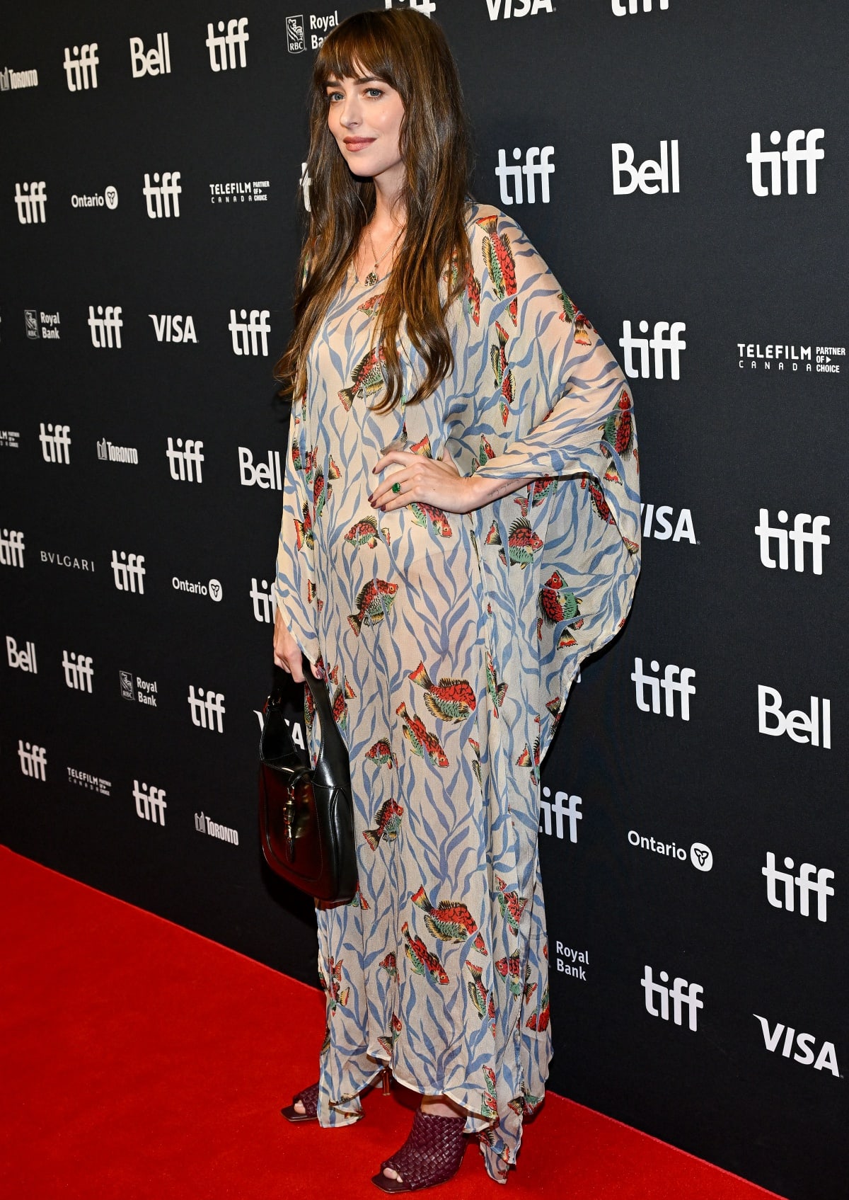Dakota Johnson carried a black leather version of the “Jackie” bag from Gucci and slipped into a pair of Bottega Veneta knot mule sandals