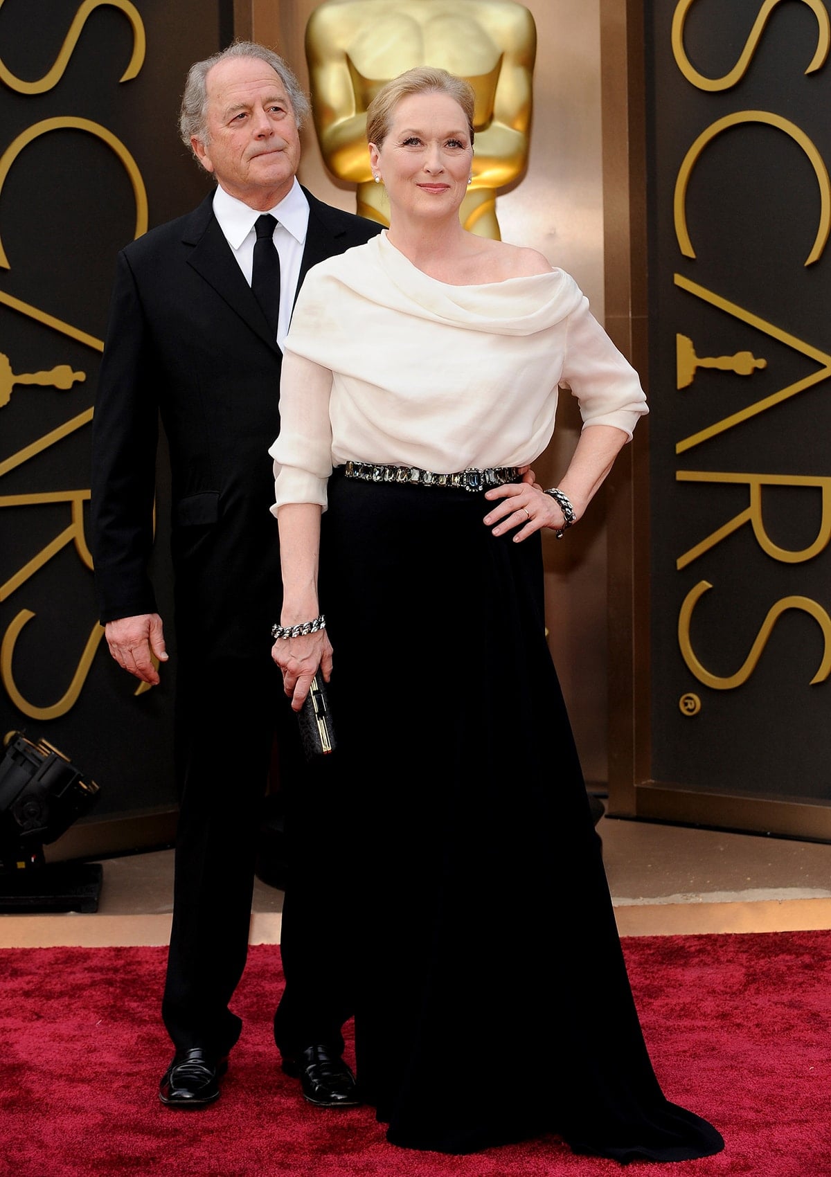 Meryl Streep exudes timeless elegance in an off-the-shoulder Lanvin gown paired with metallic accessories, while Don Gummer keeps it classic in a black suit and tie at the 2014 Oscars