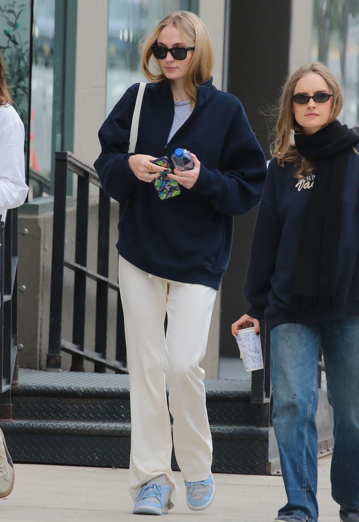 Sophie Turner teams a navy boyfriend sweatshirt by TNA with cream sweatpants and Jordan 1 low sneakers in Football Grey Aluminum