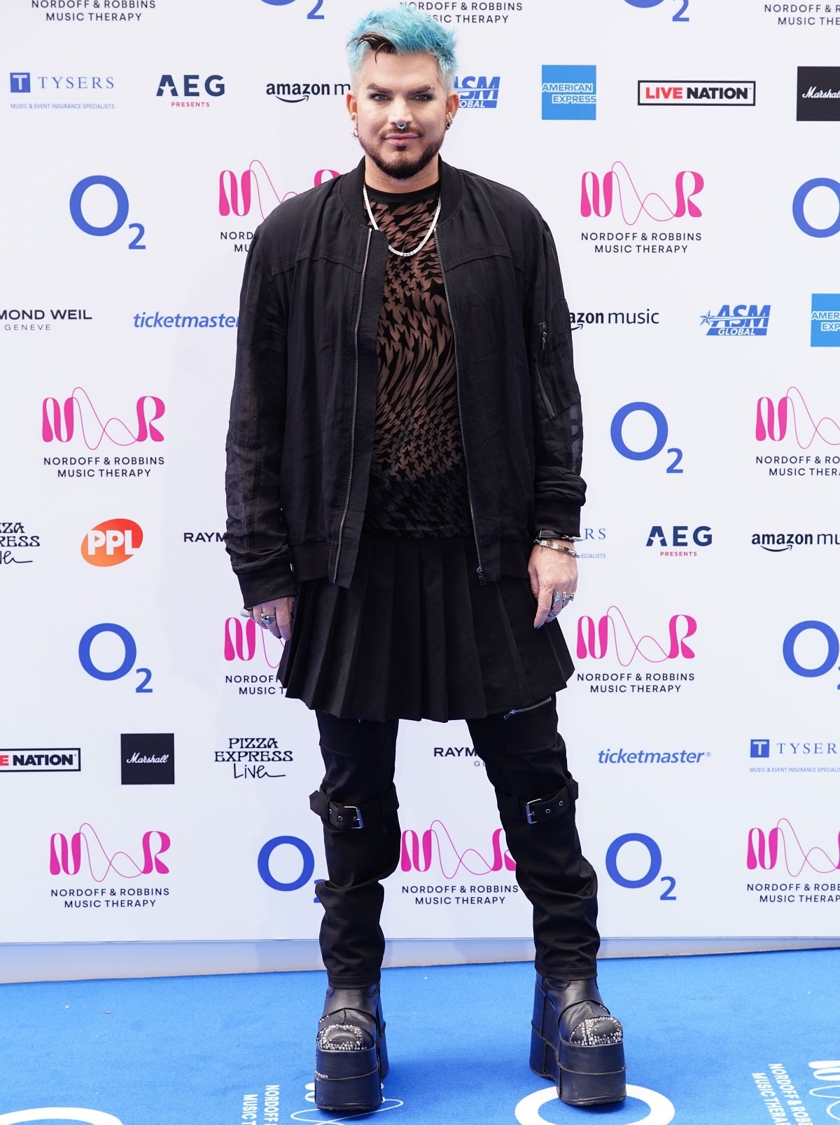 Adam Lambert turns heads in towering platform boots, buckled pants, and a pleated skirt layered over a graphic top and bomber jacket at the Nordoff Robbins Music Therapy event
