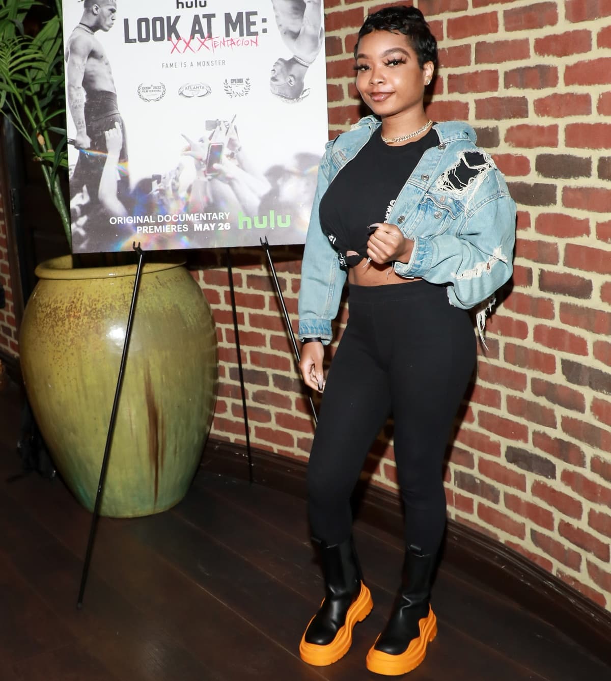 Lola Brooke kept it edgy and casual in a cropped distressed denim jacket, black leggings, and standout two-tone platform boots with bold orange soles