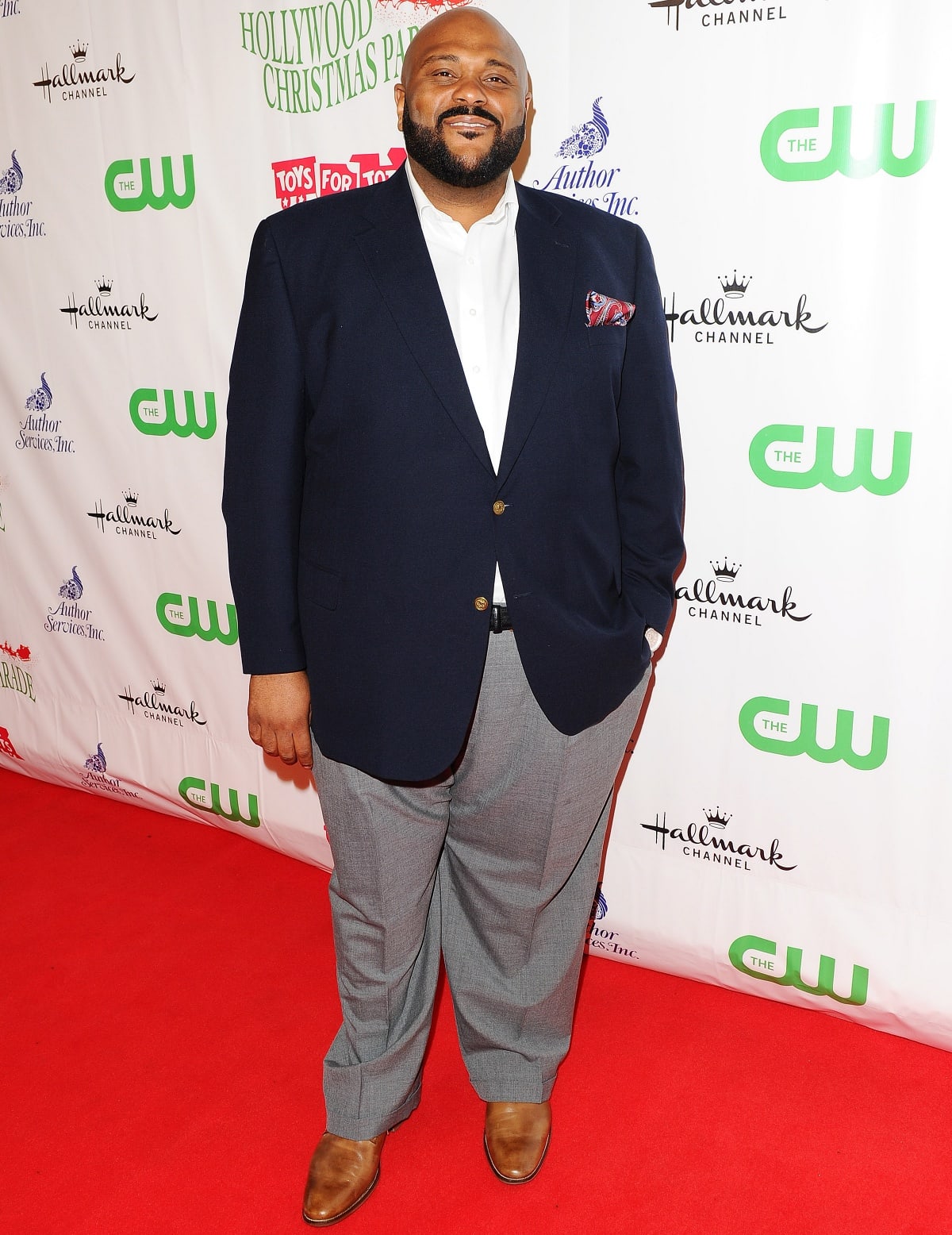 Ruben Studdard looks polished on the red carpet in a navy blazer with a paisley pocket square, gray dress pants, and classic brown leather shoes