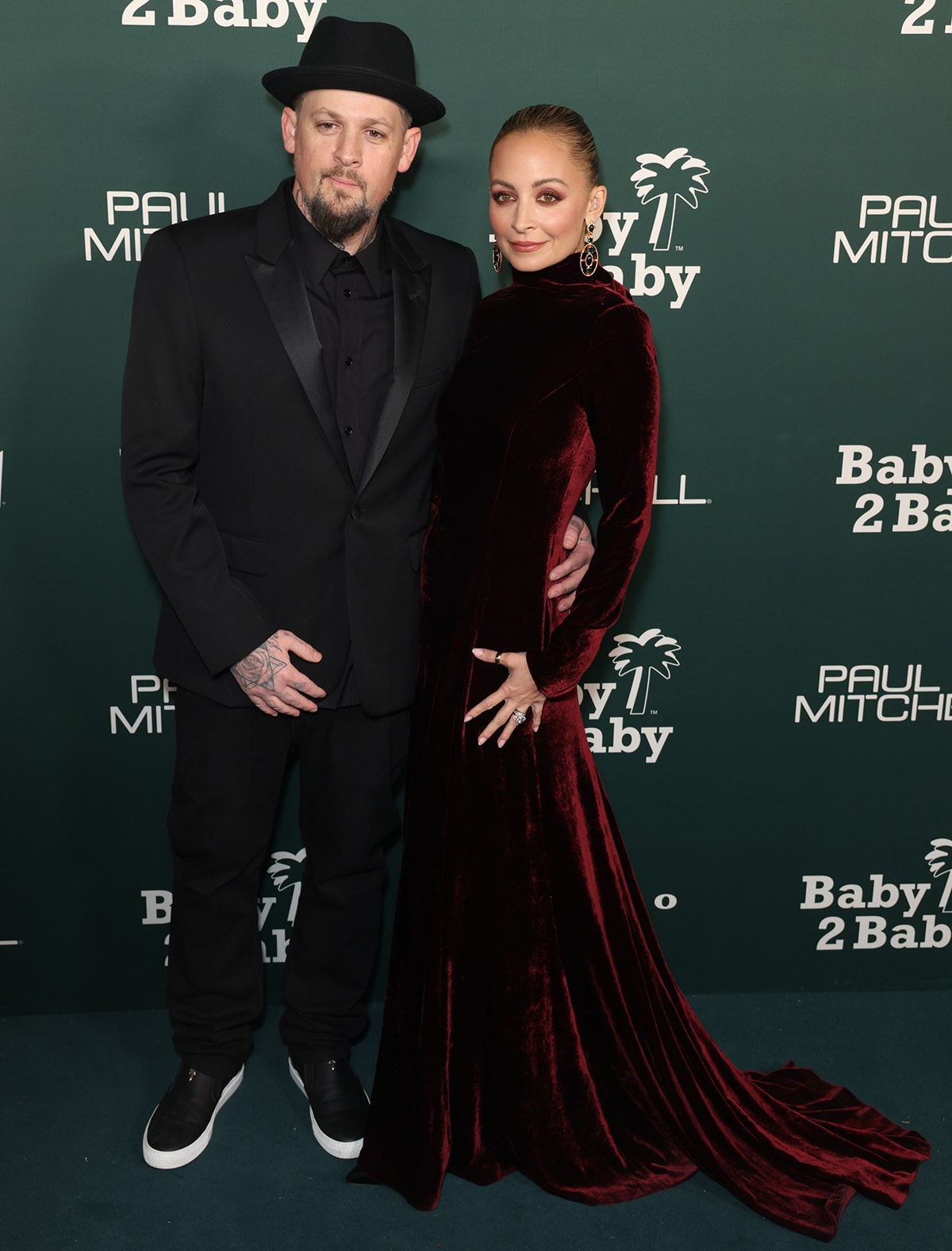 Nicole Richie poses with her husband of 17 years Joel Madden, who's clad in a black suit, white-soled black sneakers, and a black fedora
