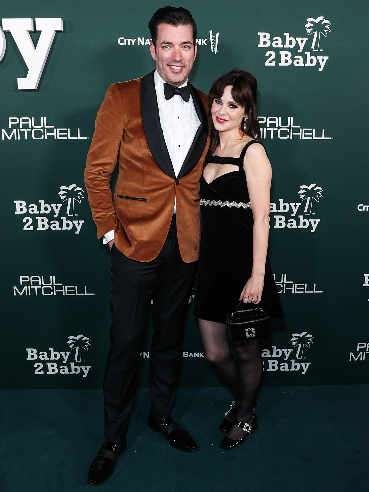 Zooey Deschanel and Jonathan Scott charm on the Baby2Baby Gala red carpet, with Zooey in a retro black velvet Patou mini and Jonathan in a brown velvet tuxedo jacket with black lapels