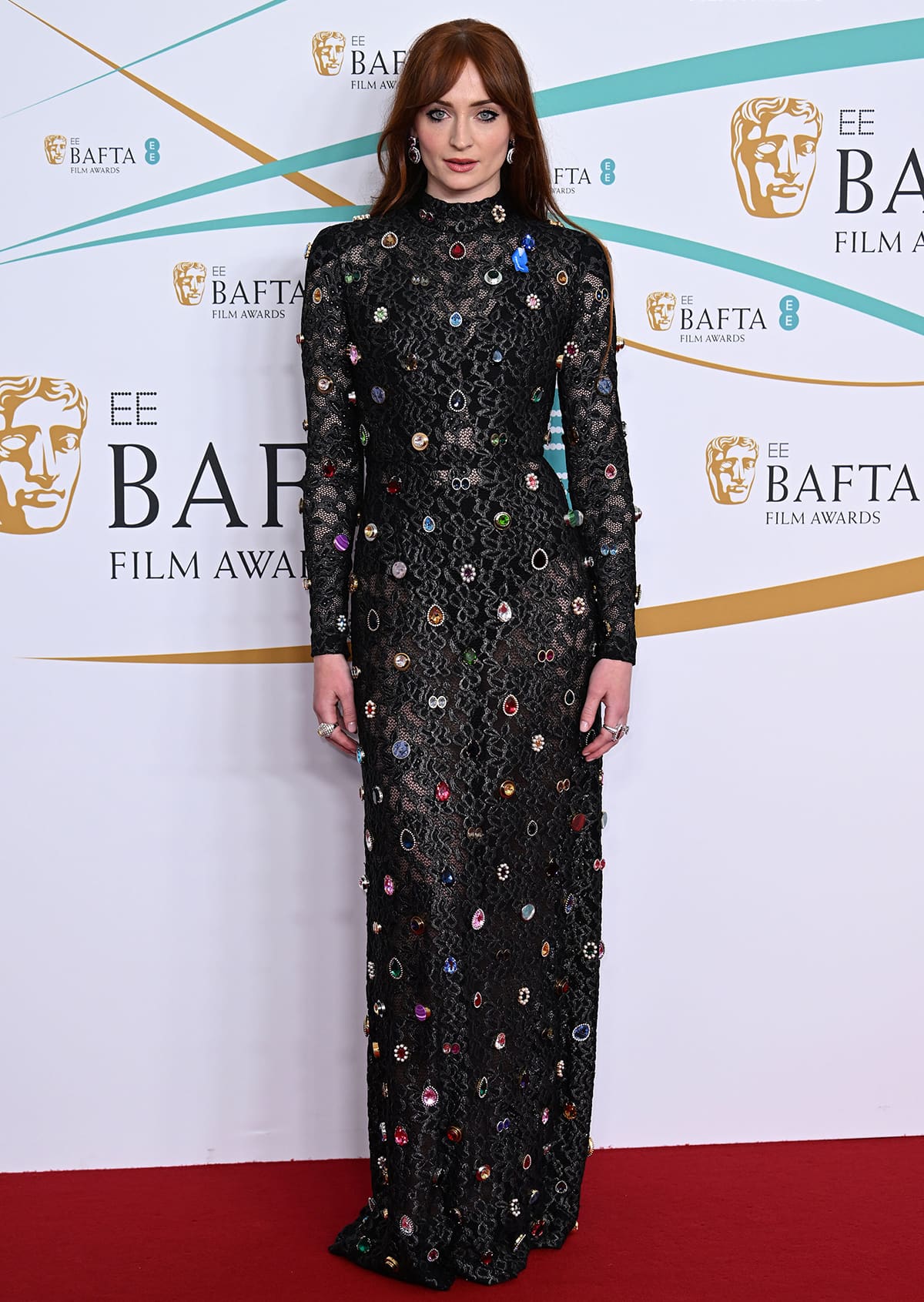 Sophie Turner stuns in a custom long-sleeved Louis Vuitton lace gown embellished with vibrant gemstones at the 2023 BAFTAs held at London’s Royal Festival Hall