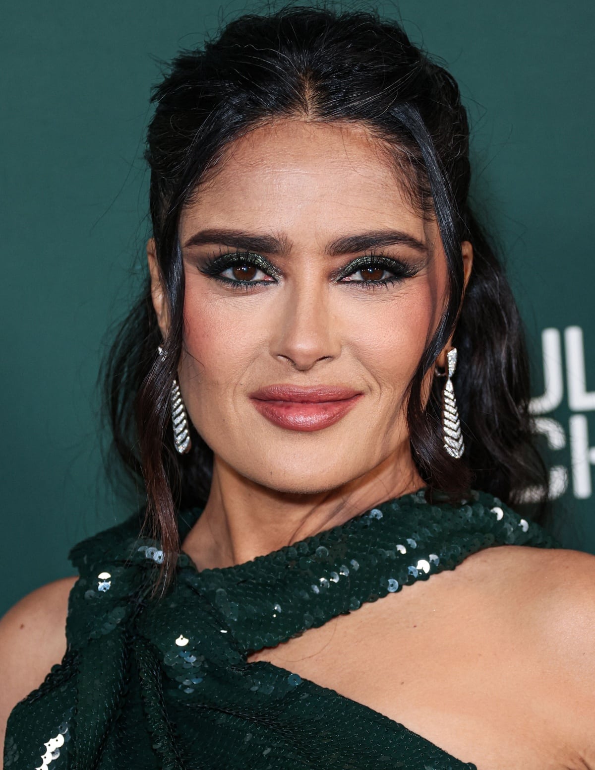 Salma Hayek’s beauty look consisted of an elegant half-up and half-down hairstyle, a pink-nude lip, sparkly green eyeshadow, and Boucheron diamond drop earrings