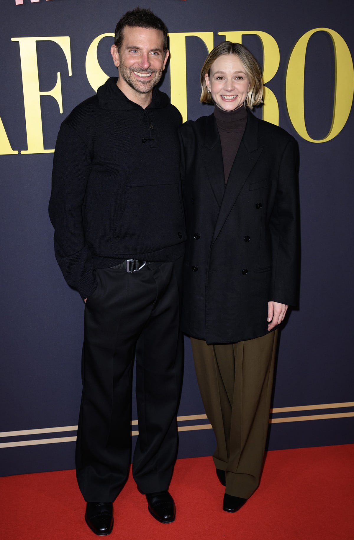Bradley Cooper and Carey Mulligan coordinate in understated black ensembles at the London premiere of Maestro, with Cooper in polished dress shoes and Mulligan grounding her minimalist look with square-toed black heels and wide-leg trousers