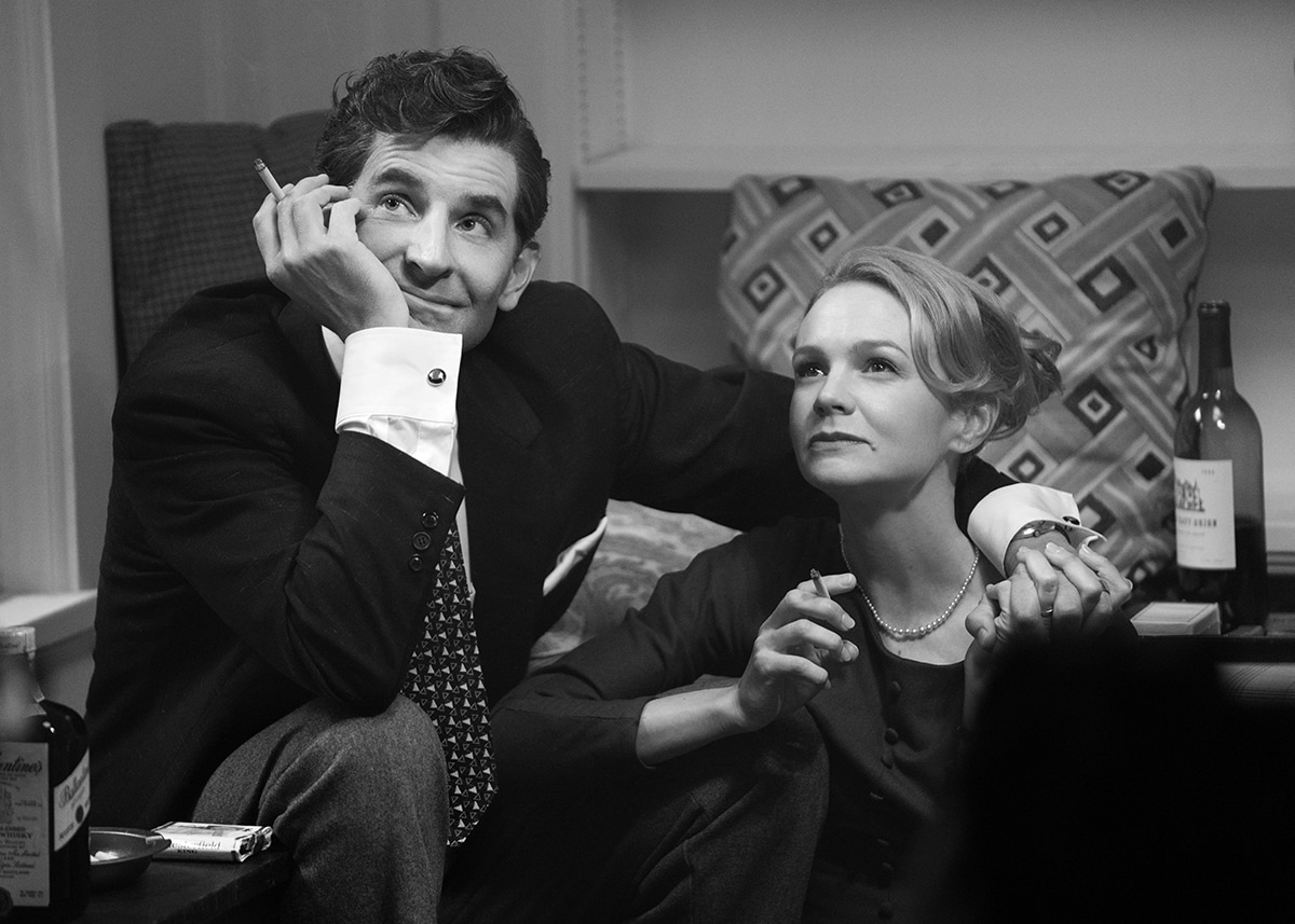 Bradley Cooper and Carey Mulligan channel vintage elegance as Leonard Bernstein and Felicia Montealegre in Maestro, captured in a nostalgic black-and-white scene with tailored 1940s-inspired suiting and pearl-accented styling