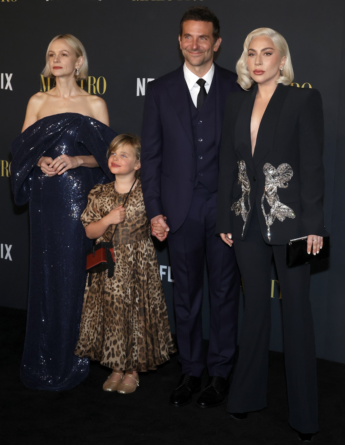 Carey Mulligan sparkles in a navy sequin gown as she poses with co-star Bradley Cooper, his daughter Lea De Seine in a leopard-print dress, and Lady Gaga in a plunging black Alexander McQueen suit adorned with crystal orchid embroidery at the Los Angeles premiere of Maestro