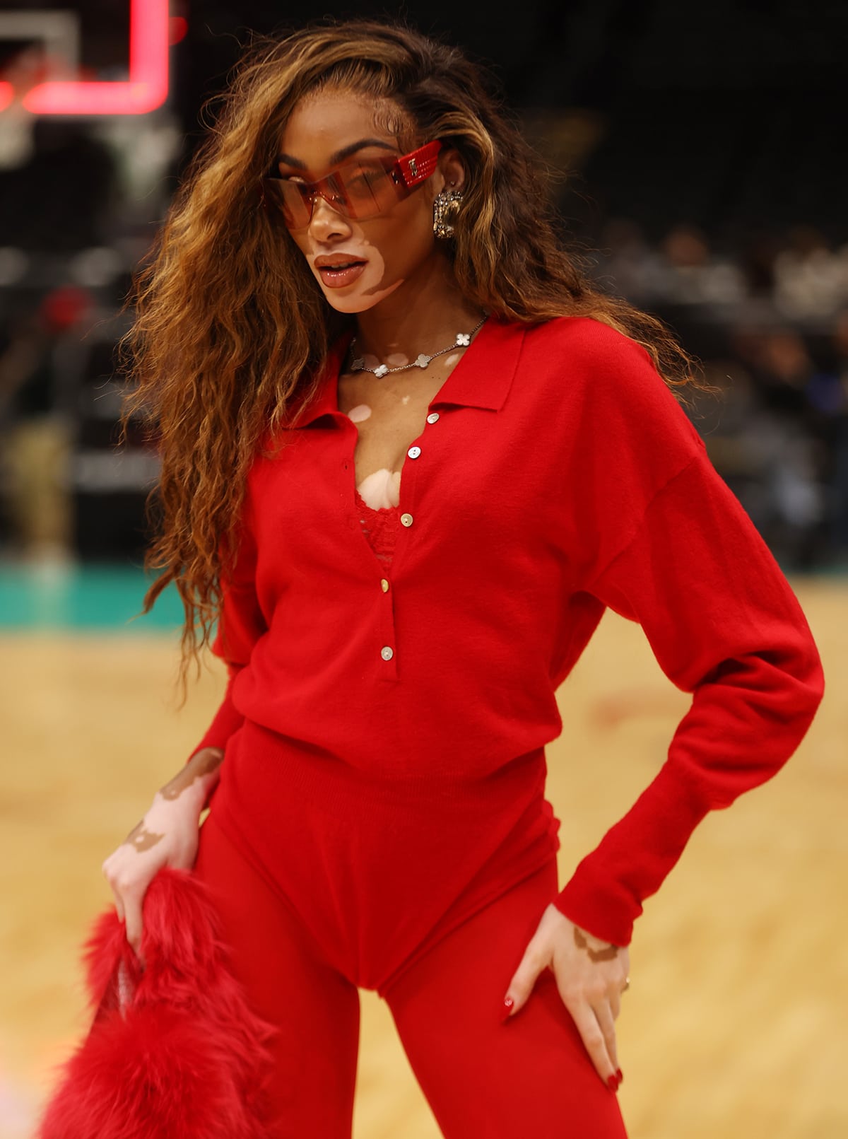 Winnie Harlow styles her all-red look with chunky diamond-embellished earrings and a Van Cleef Arpels Alhambra necklace with white mother-of-pearl