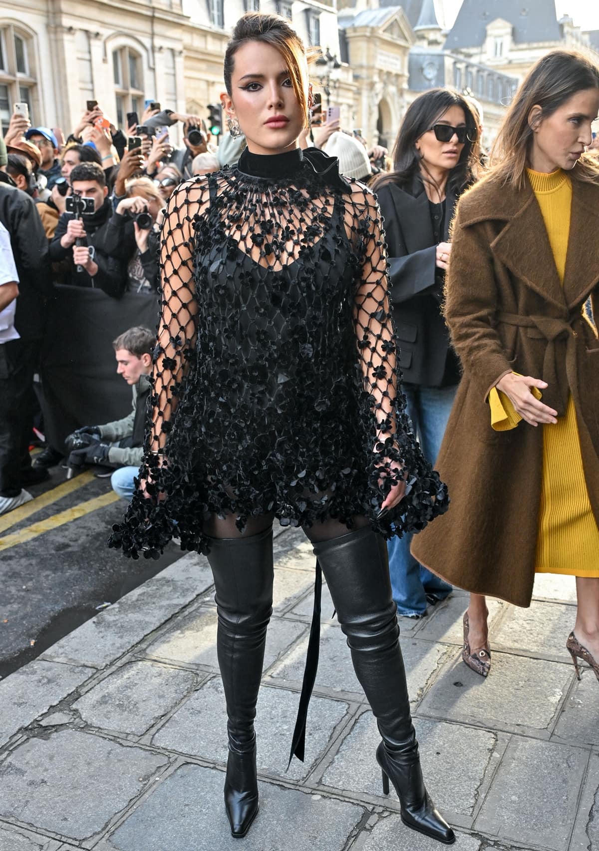 Bella Thorne exudes chic sophistication in a black strapless mini dress with a floral net overlay at the Jean Paul Gaultier Haute Couture show as part of Paris Fashion Week on January 24, 2024 in Paris, France