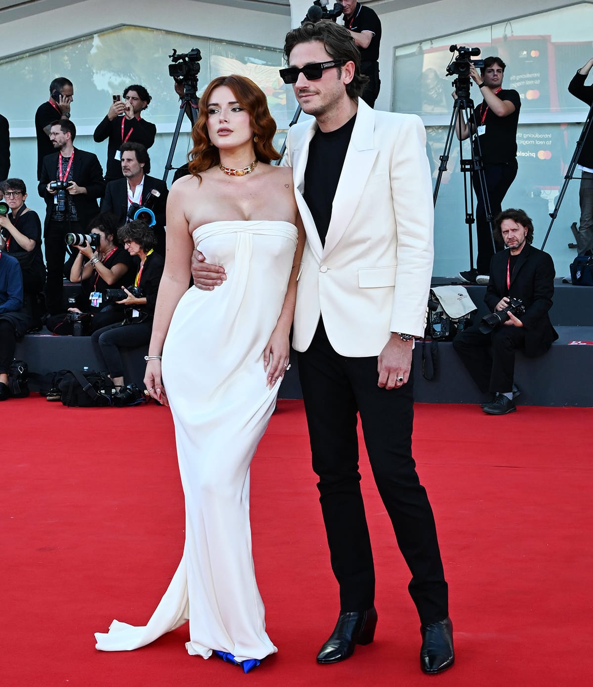 Bella Thorne and fiancé Mark Emms coordinated in elegant ivory looks at the Priscilla premiere during the 80th Venice International Film Festival on September 4, 2023, with the actress finishing her strapless Tom Ford column gown with striking cobalt-blue pointed-toe heels