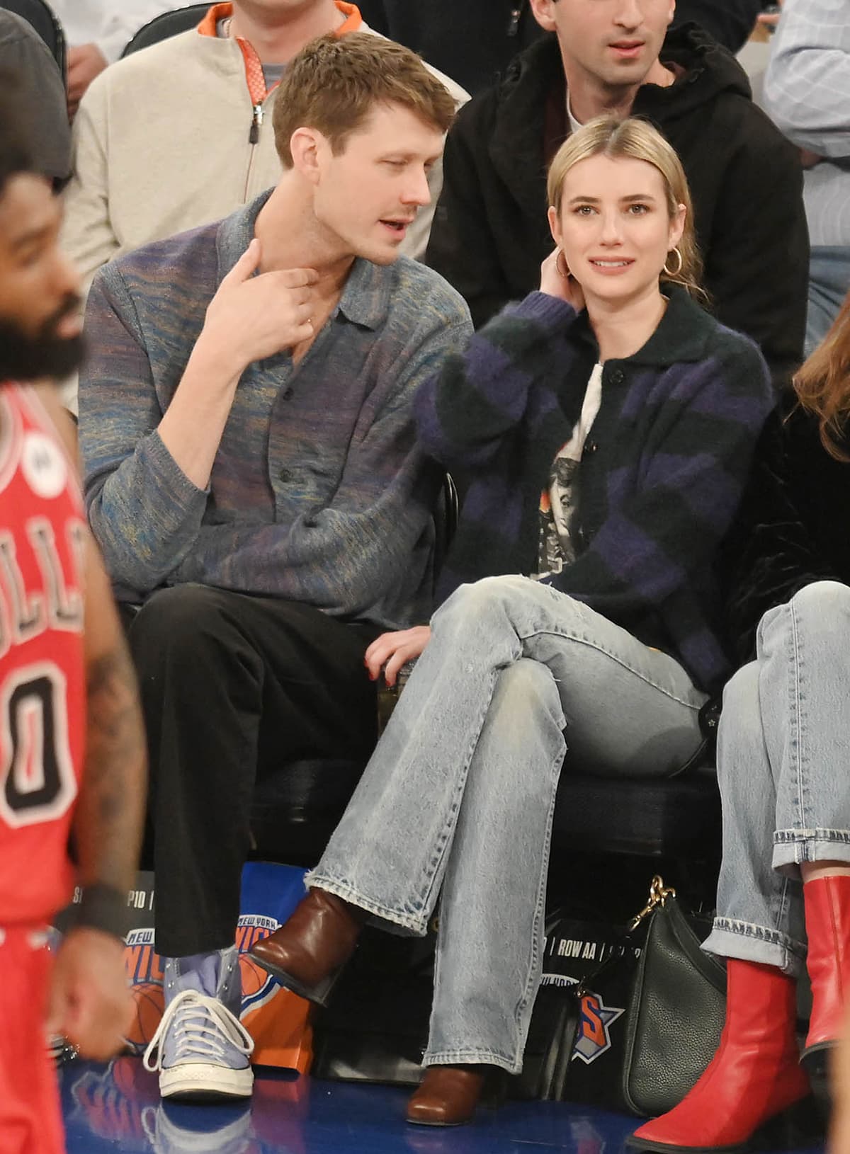 Emma Roberts keeps courtside style effortlessly polished in square-toe brown leather ankle boots, pairing their structured block heel with relaxed flared denim and a cozy striped cardigan at Madison Square Garden on January 4, 2024