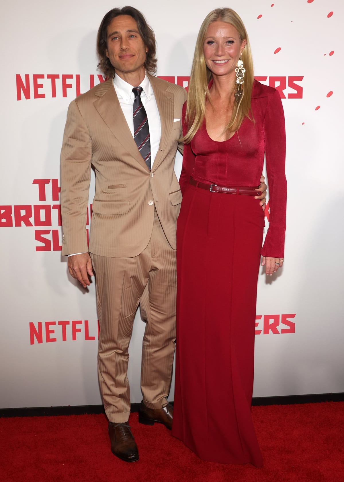 Gwyneth Paltrow joins Brad Falchuk on the red carpet at The Brothers Sun premiere at the Netflix Tudum Theater in Los Angeles on January 4, 2024, wearing a striking monochrome red look that elongates her silhouette with clean, uninterrupted lines