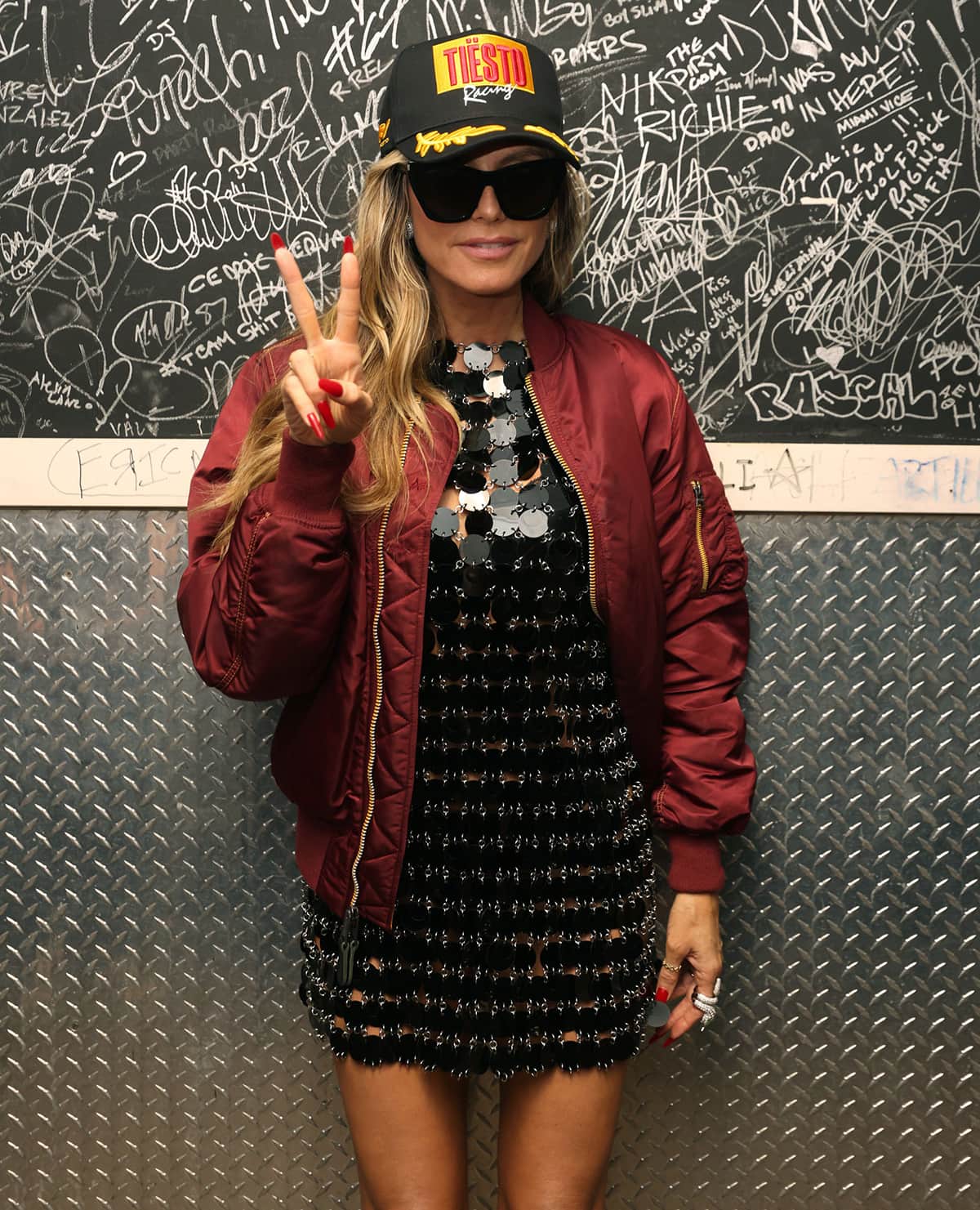 Heidi Klum gives her flirty LBD a dash of cool factor by accessorizing with a red bomber jacket and a DJ Tiesto cap