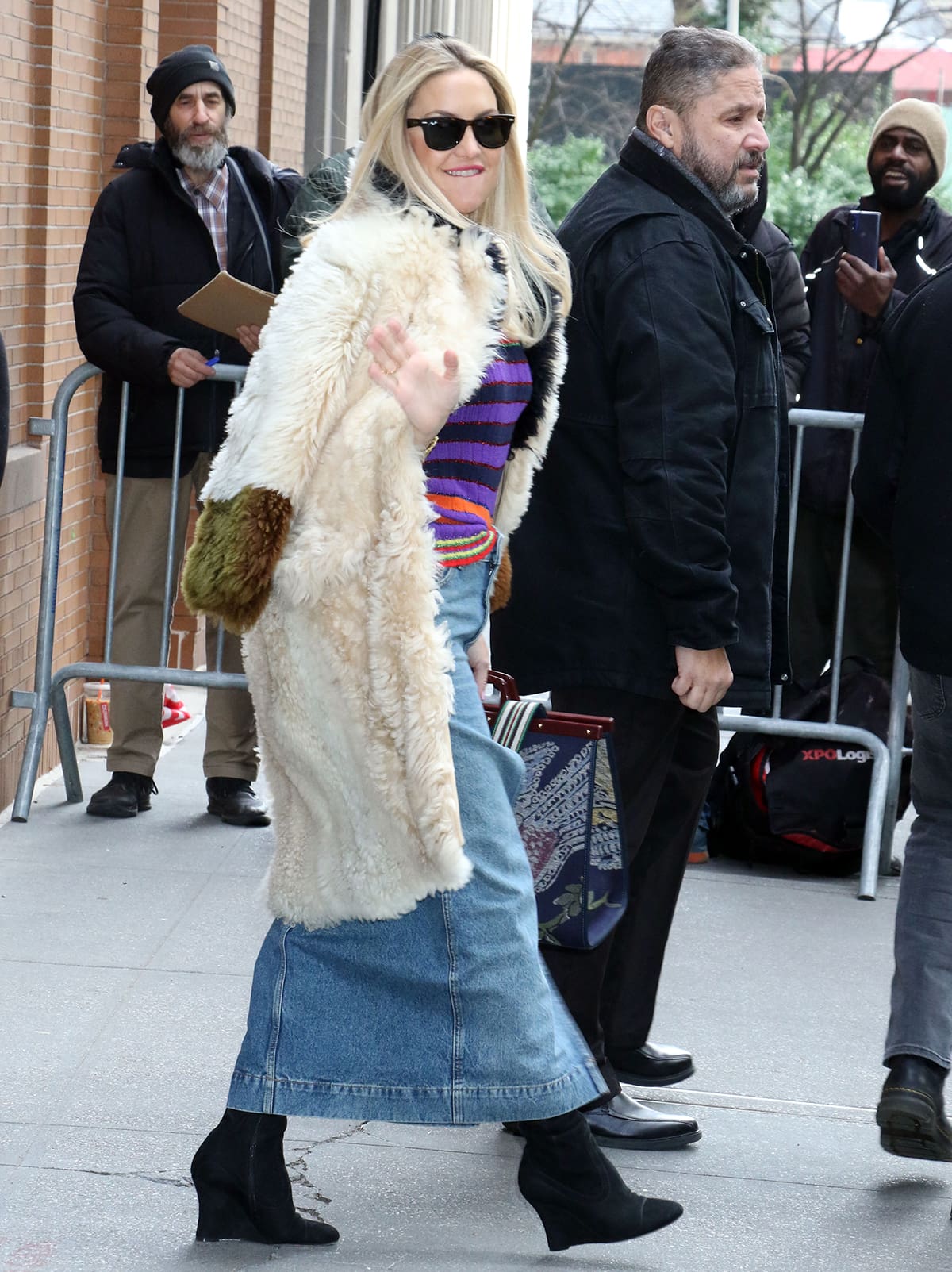 Kate Hudson grounds her colorful Gucci striped sweater and denim midi skirt with sleek black suede boots, the pointed toes and sculpted heels adding a sharp, modern counterpoint beneath a plush Marni shearling coat