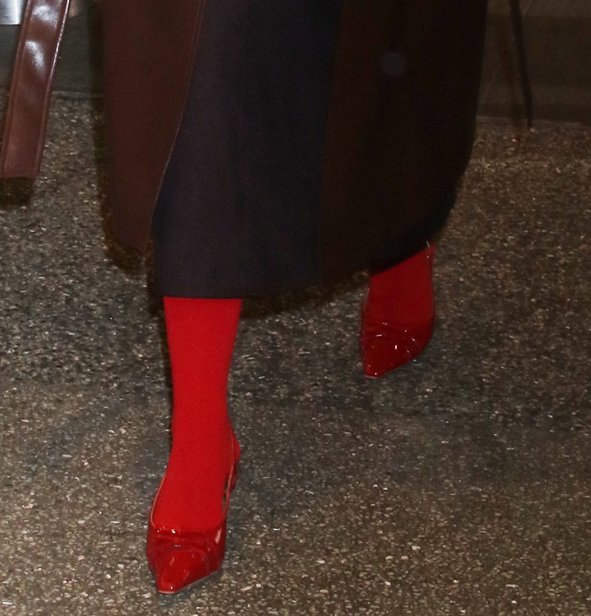 Camila Mendes pairs her brown outfit with red tights and red Reformation slingback pumps