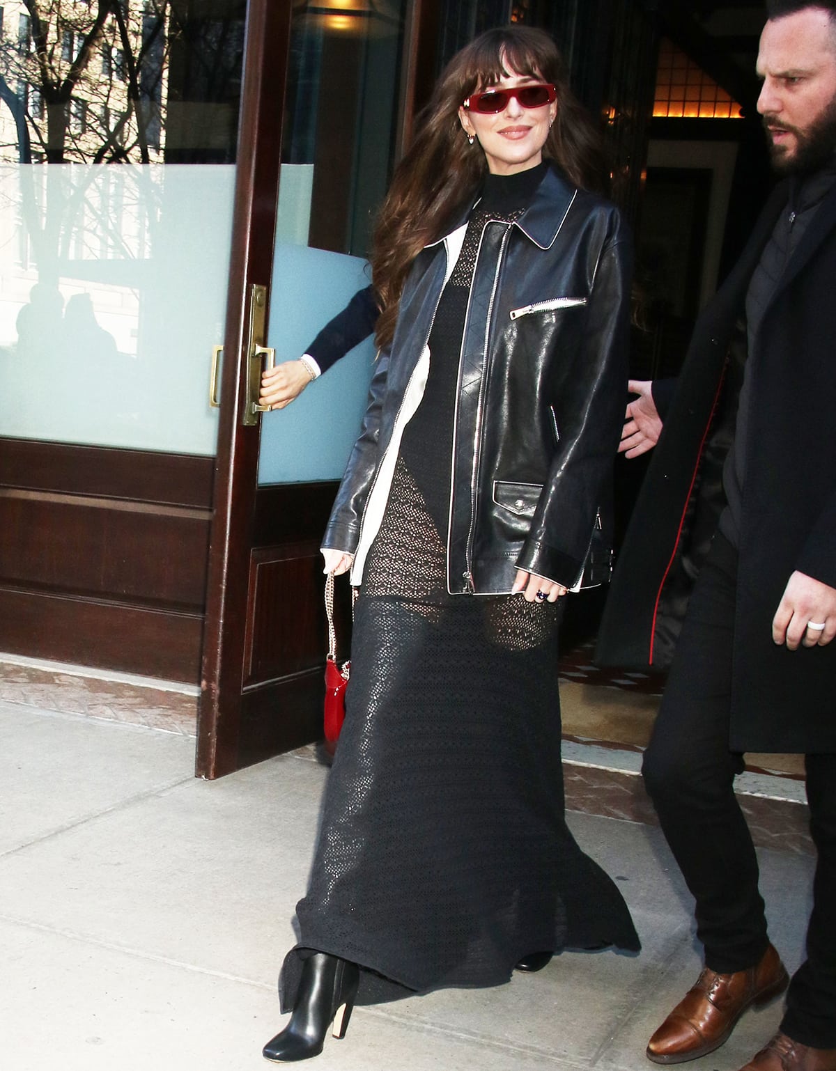 Dakota Johnson channels Madame Web in a black openwork knit maxi dress layered under a sleek leather jacket and paired with sculptural black Bottega Veneta over-the-knee boots