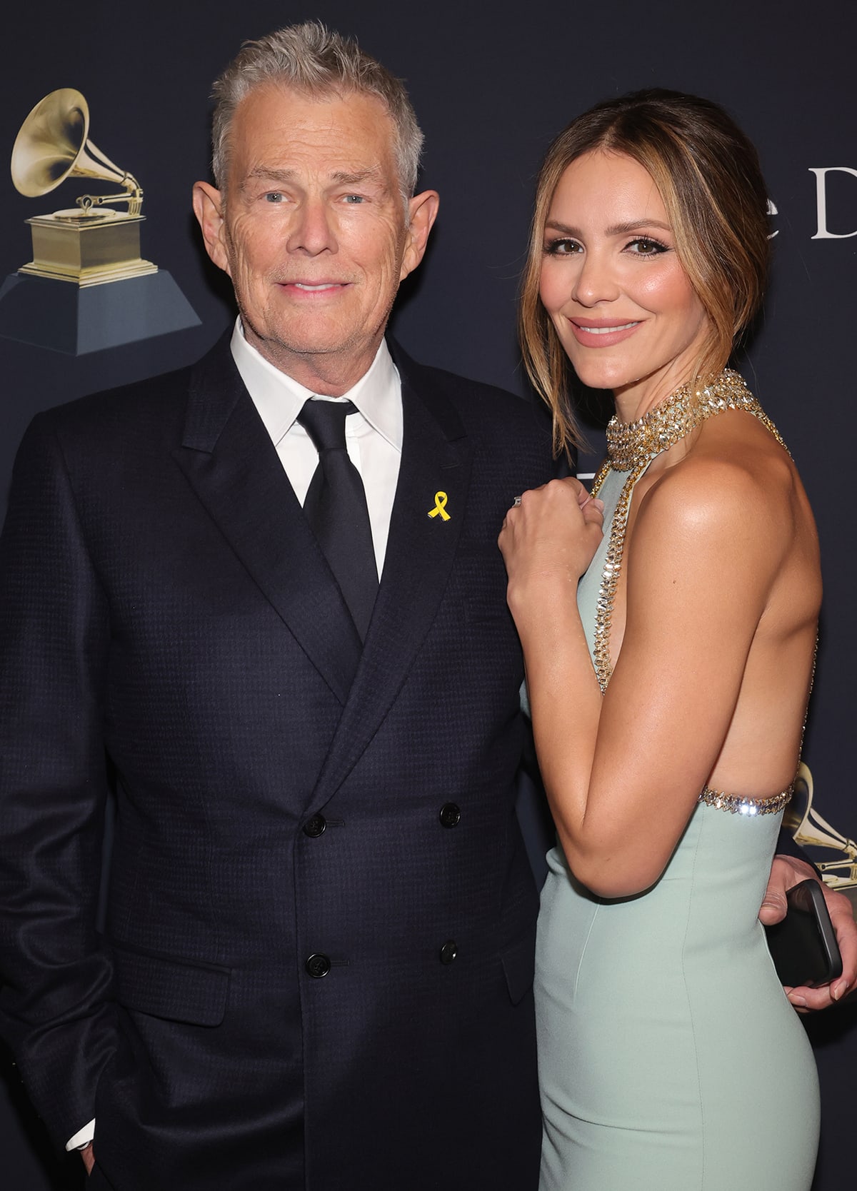 David Foster opts for a classic menswear suit with a double-breasted jacket, white shirt, and a black tie