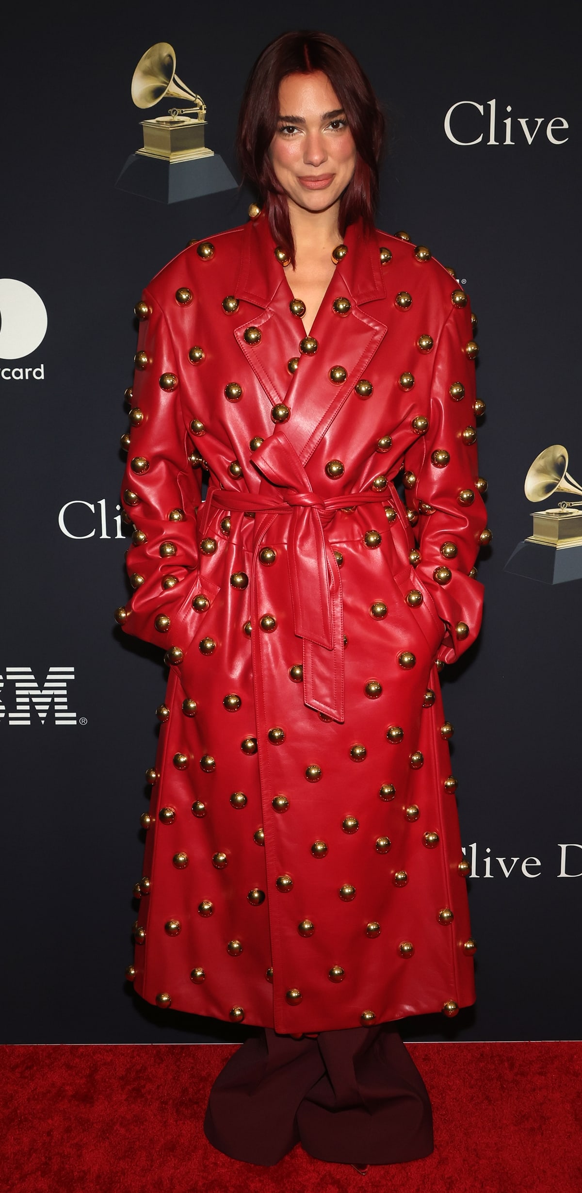 Making a striking entrance at Clive Davis’ Pre-Grammys party in Los Angeles, Dua Lipa showcased her unique style in a bold red Valentino leather trench coat from the Spring/Summer 2024 collection