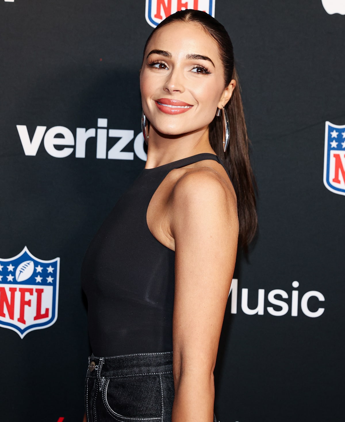 Olivia Culpo accessorizes with Tiffany Co. jewelry and glams up with rosy makeup and a high center-parted ponytail