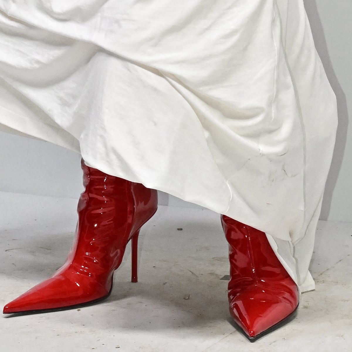 Emily Ratajkowski makes a bold statement with cherry red patent leather boots, infusing a vibrant pop of color and undeniable chic into her ensemble