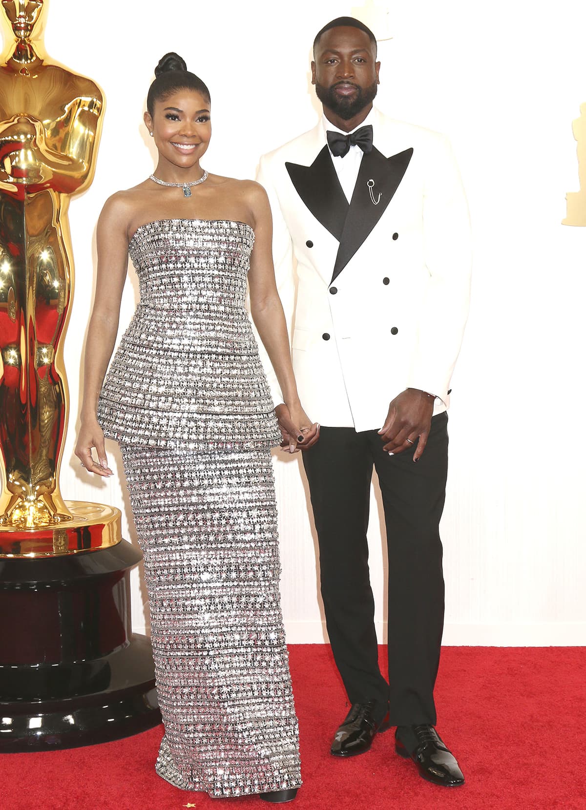 Gabrielle Union sparkles in a crystal-embellished Carolina Herrera look with black Stuart Weitzman Nudist Hollywood platform sandals as she poses with her husband Dwayne Wade at the 2024 Oscars on March 10, 2024