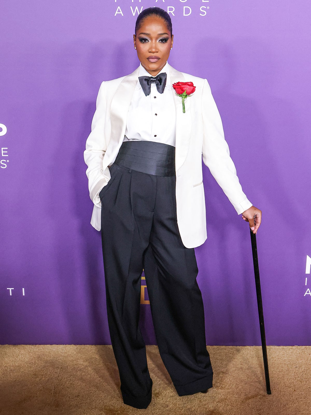 Keke Palmer looks sharp in a white tuxedo jacket with a white shirt and a black bowtie from Tom Ford teamed with a pair of wide-leg trousers and pumps by Dolce Gabbana