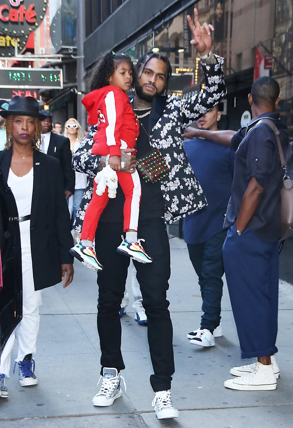 Dave East turns heads in a floral blazer, black pants, and high-top sneakers while carrying his daughter through the streets of New York