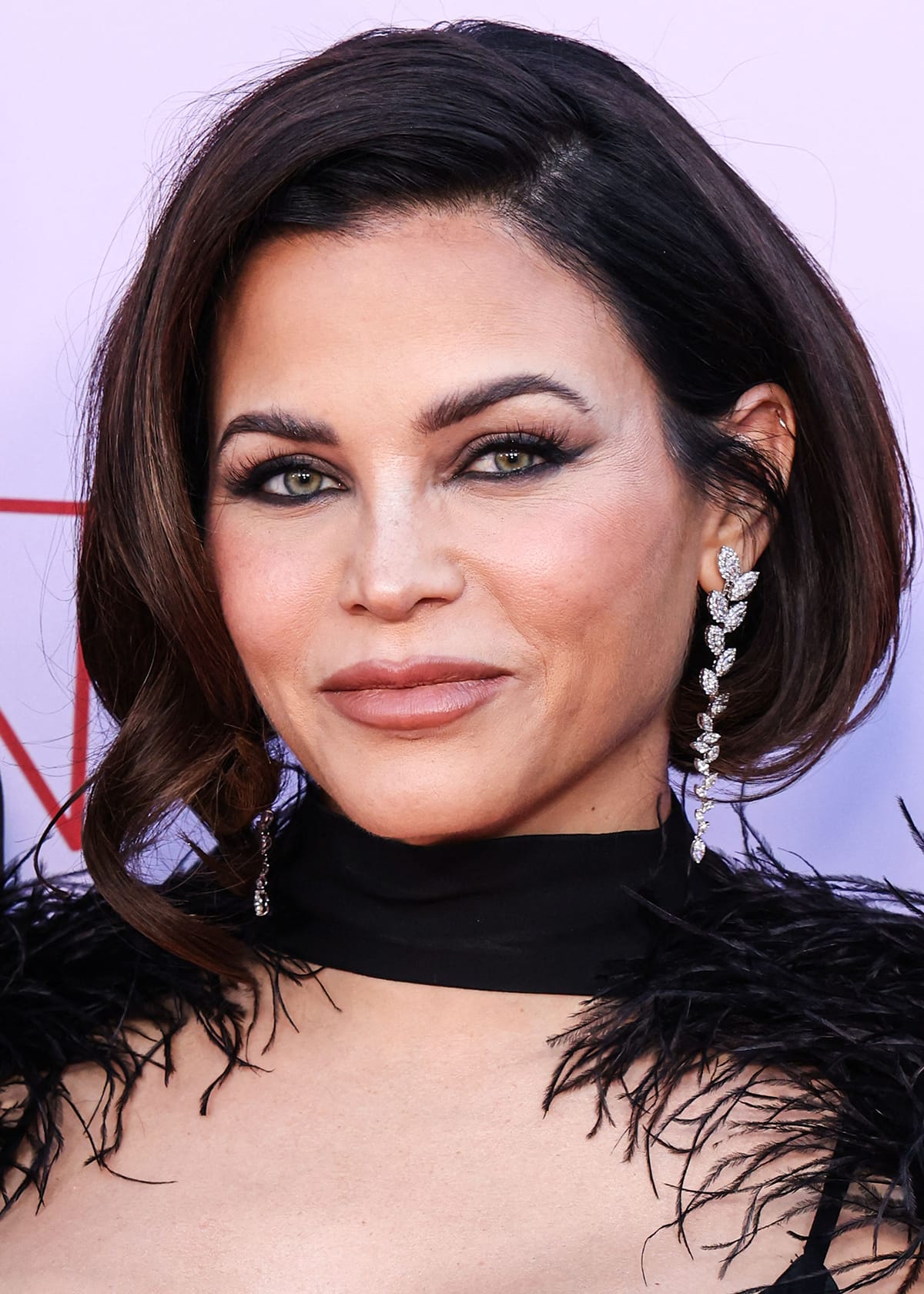 Jenna Dewan debuts a shorter bob hairstyle and completes the gothic-glam theme of her black feathered look with black smoky eyeshadow, kohl-rimmed eyes, and nude pink lipstick