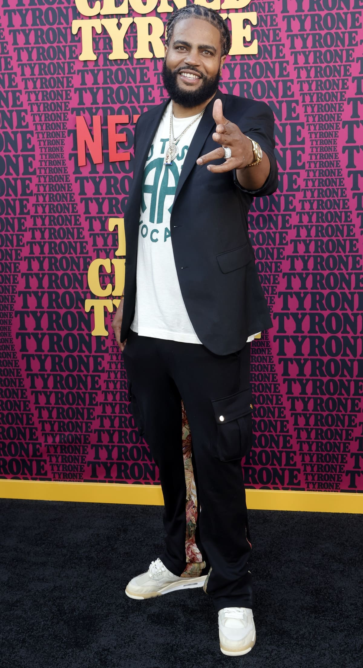 Kia Shine keeps it casual and confident in a graphic tee, blazer, cargo joggers with floral side panels, and white sneakers at the They Cloned Tyrone premiere