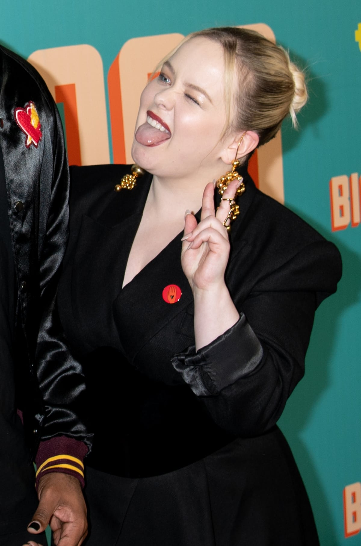 A pop of color in a sea of black: Nicola Coughlan's red badge stands out against her sophisticated monochrome ensemble