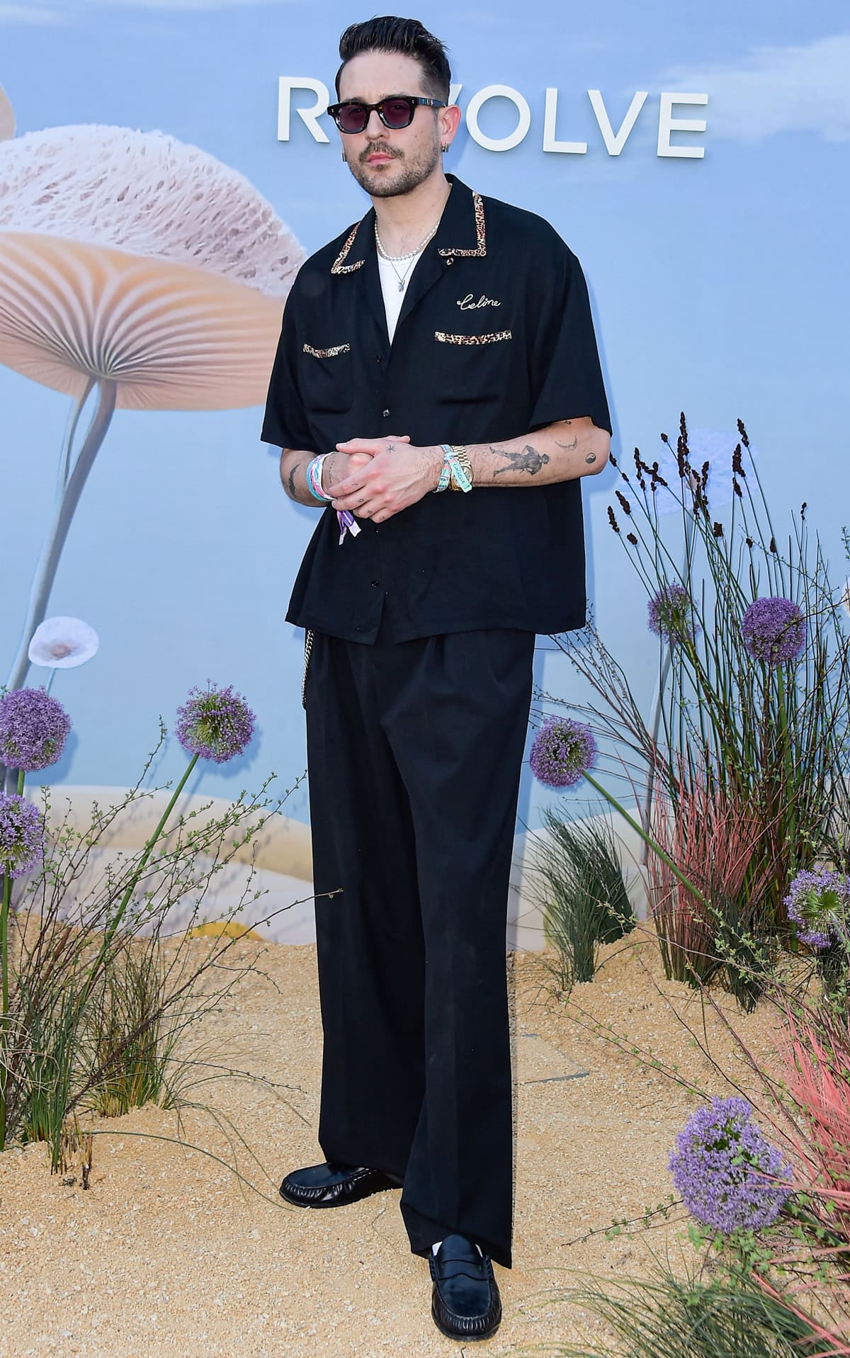 G-Eazy keeps it cool in a black Celine shirt with leopard trim and matching trousers, finishing the look with sleek black moccasin-style loafers at the Revolve Festival