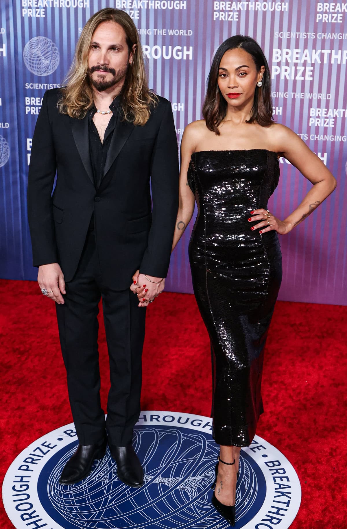 Zoe Saldaña exudes sleek, modern glamour in a strapless sequined Givenchy dress and sharp black ankle-strap pumps as she joins Marco Perego at the 10th Annual Breakthrough Prize Ceremony on April 14, 2024