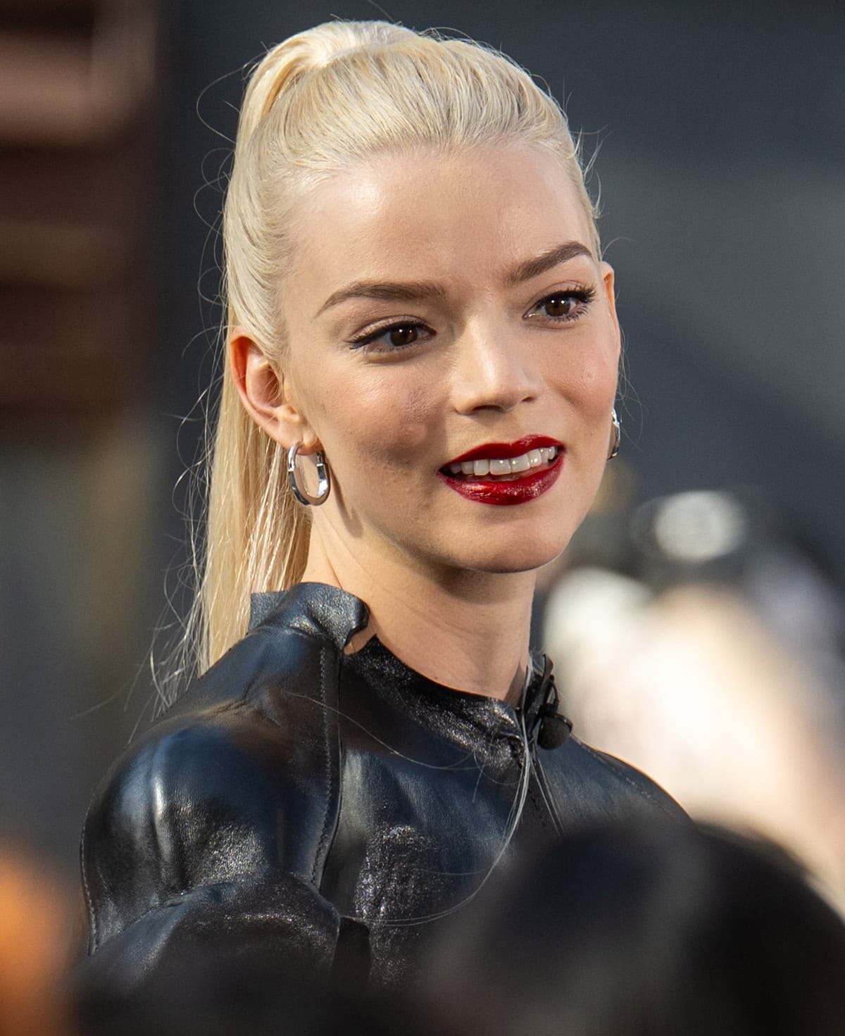 Anya Taylor-Joy looks flawless with a sleek high ponytail, mascara, and bold red lipstick