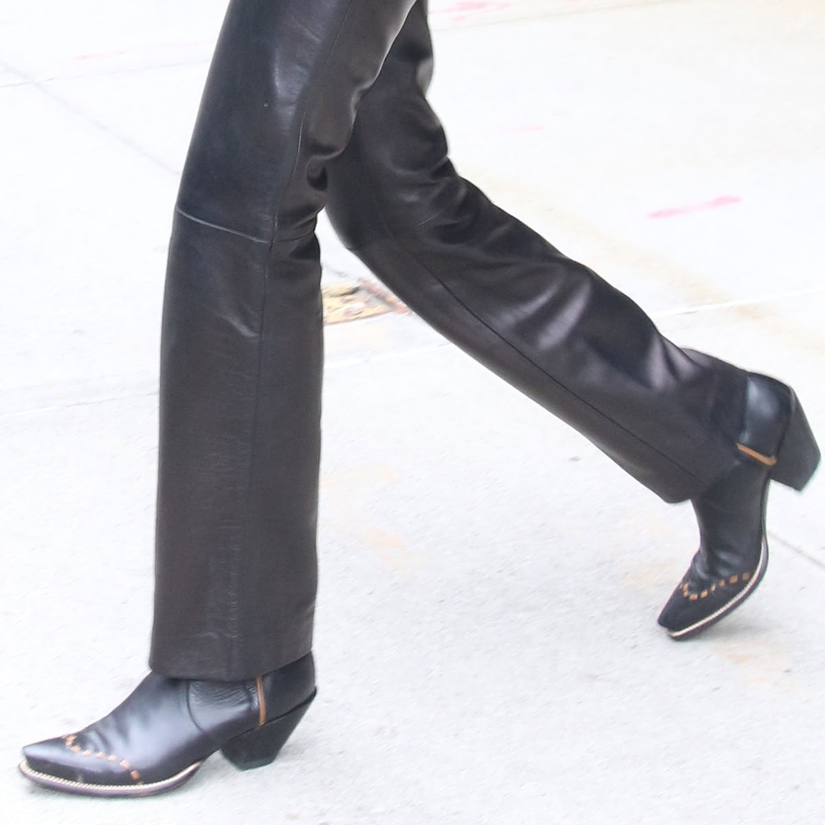 Remaining faithful to her equestrian-inspired style, Bella Hadid dons sleek black cowboy boots, infusing a touch of Y2K flair into her look