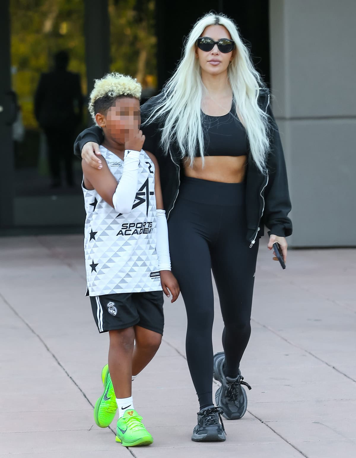 Kim Kardashian flaunts her taut abs in a black crop bralette, leggings, and jacket after cinching her waist too tight at the 2024 Met Gala