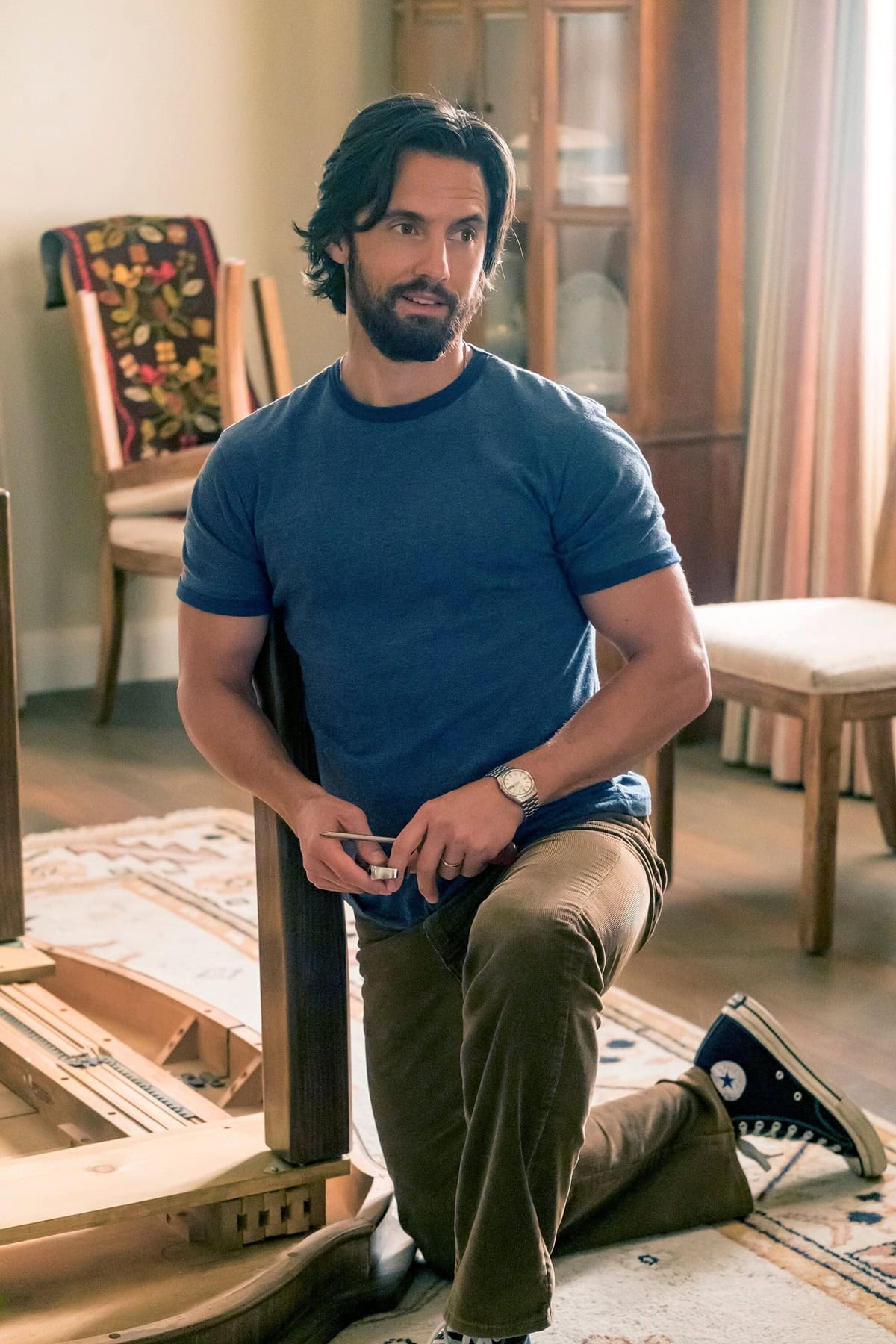 Milo Ventimiglia as Jack Pearson in This Is Us Episode 4x5, dressed casually in a blue tee and brown pants, finished with classic navy Converse Chuck Taylor sneakers
